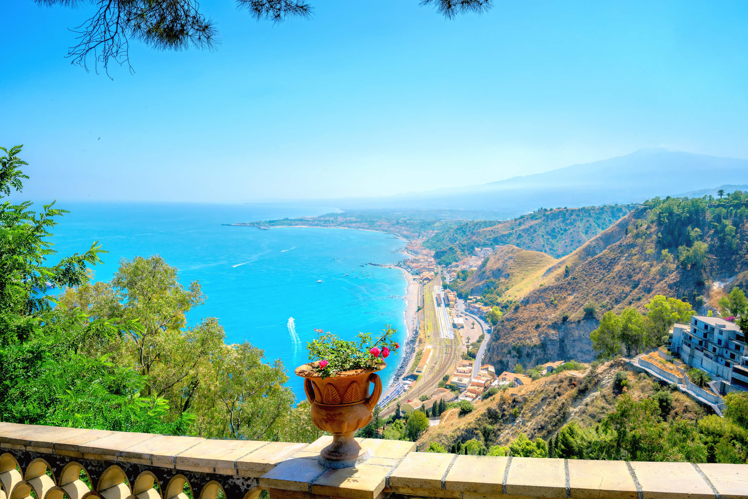 Wunderschöner Blick auf blaues Wasser, Küste und Berge mit einem Blumentopf im Vordergrund. Herrliches Wetter!