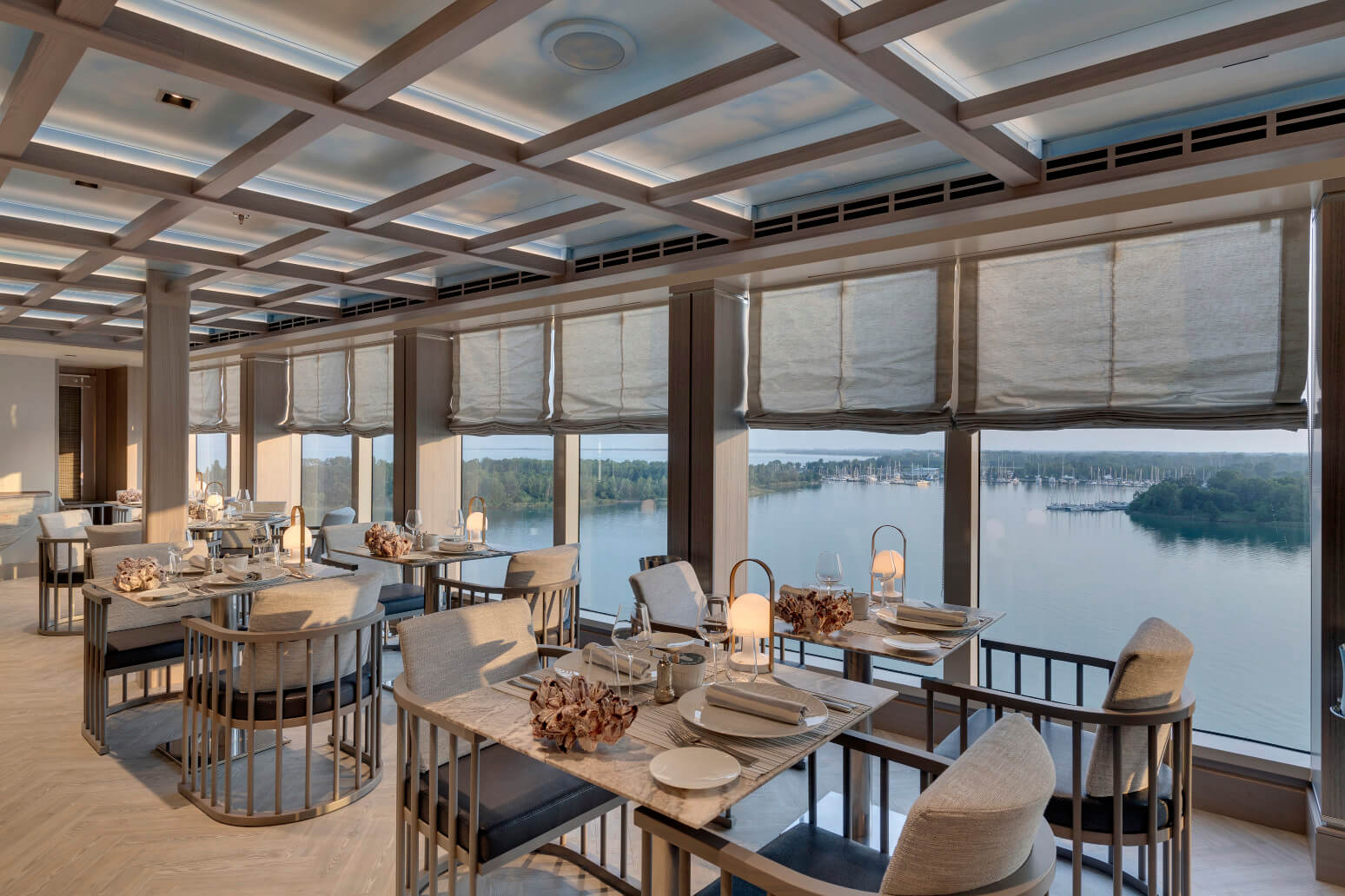 Moderne Restaurant mit Panoramablick auf einen See, stilvolle Tische und elegante Einrichtung.