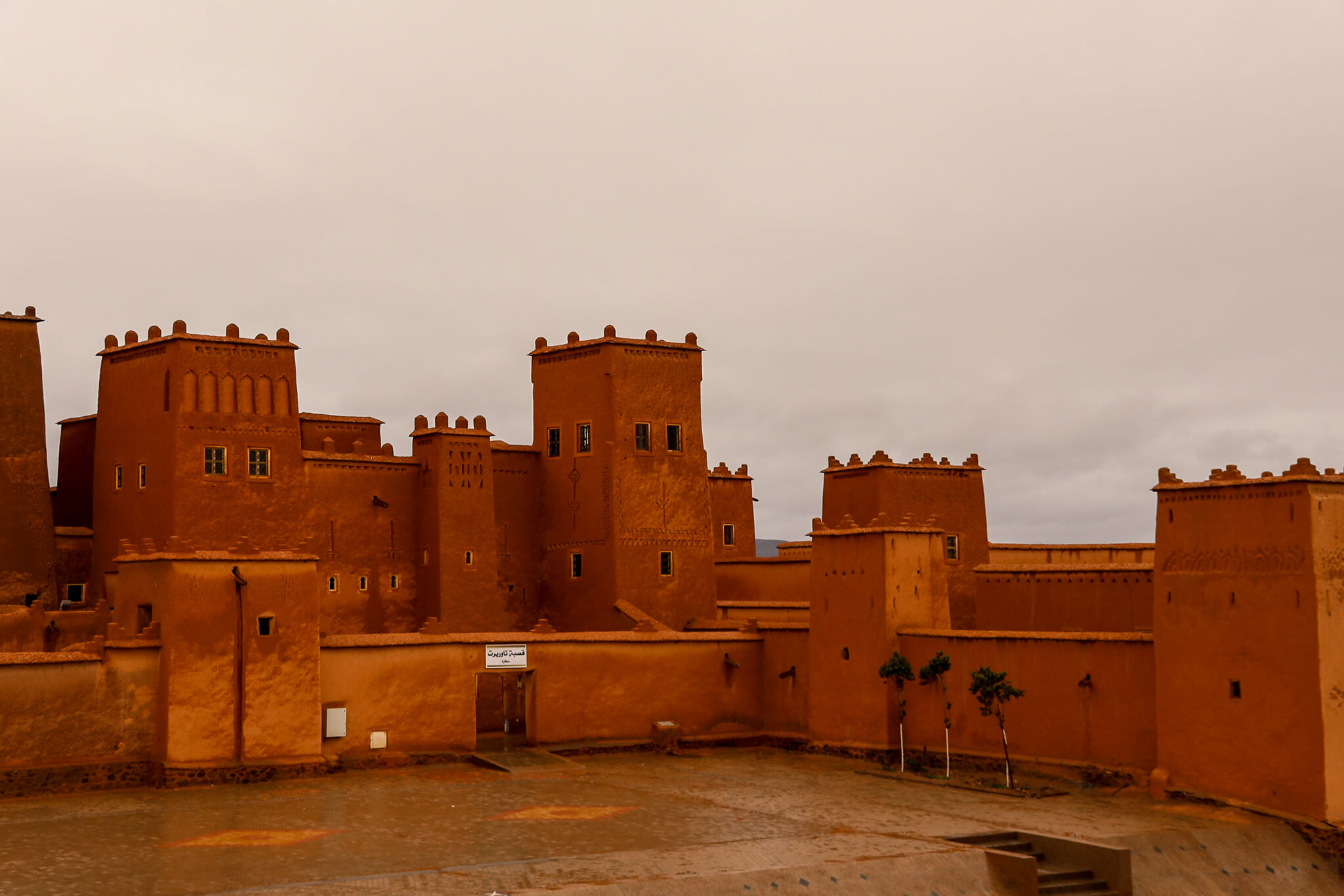 Eine beeindruckende, orangefarbene Festung mit Türmen und traditionellen architektonischen Elementen unter bewölktem Himmel.