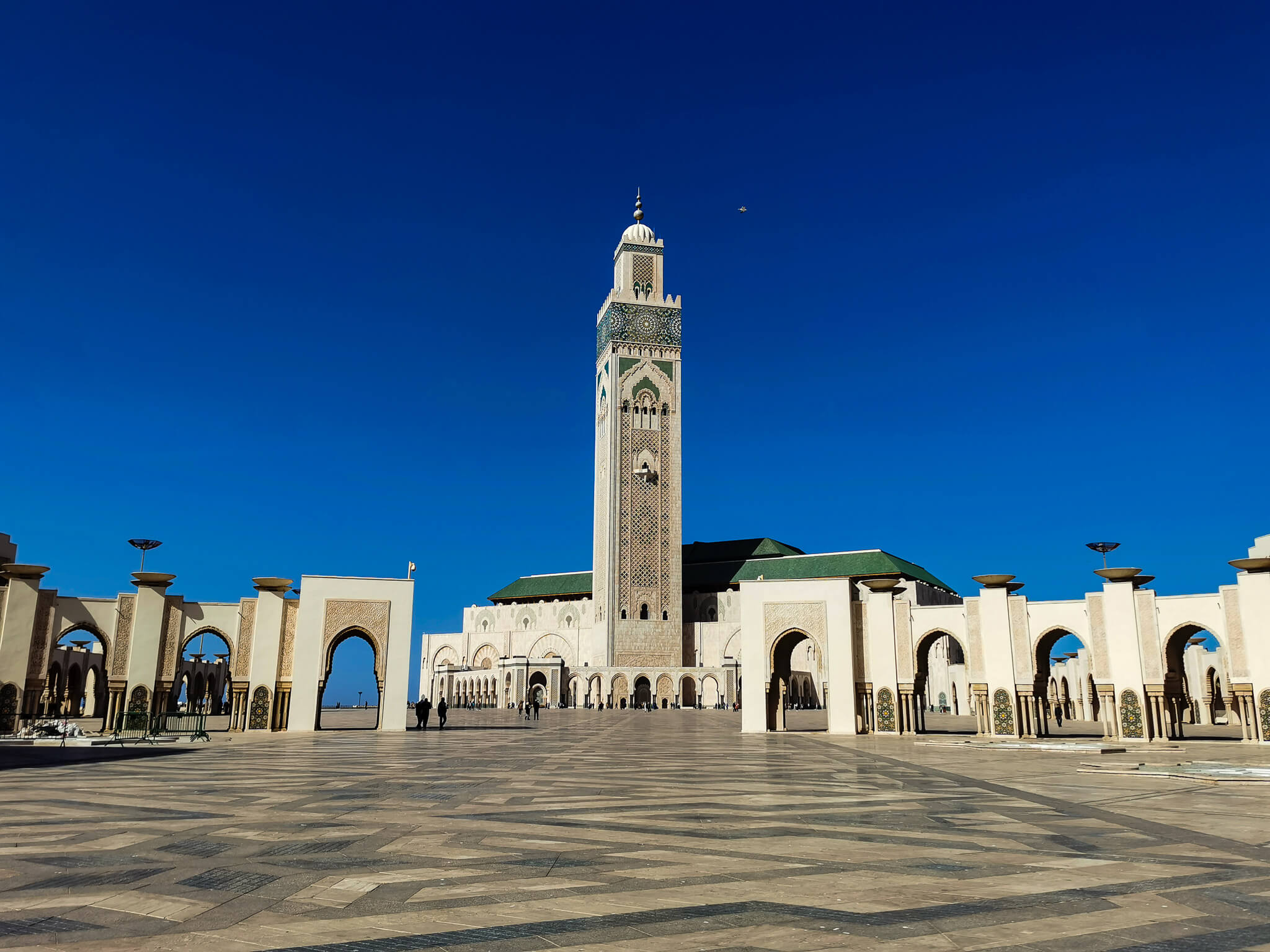 Ein klarer Himmel über einer beeindruckenden Moschee mit einem hohen Minarett und schönen Arkaden.