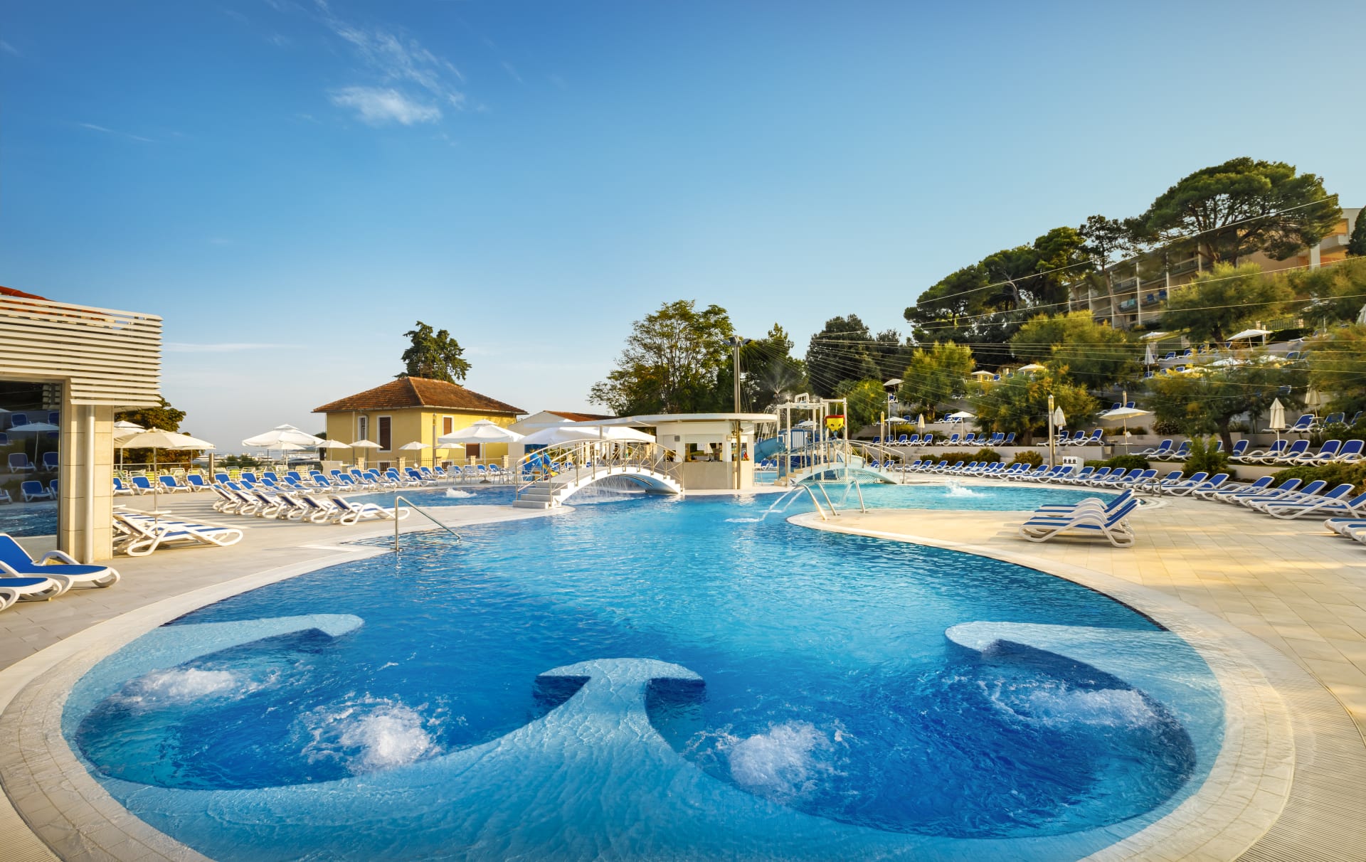 Ein schöner Pool mit Sonnenliegen, umgeben von Natur und einem klaren Himmel. Entspannung pur!