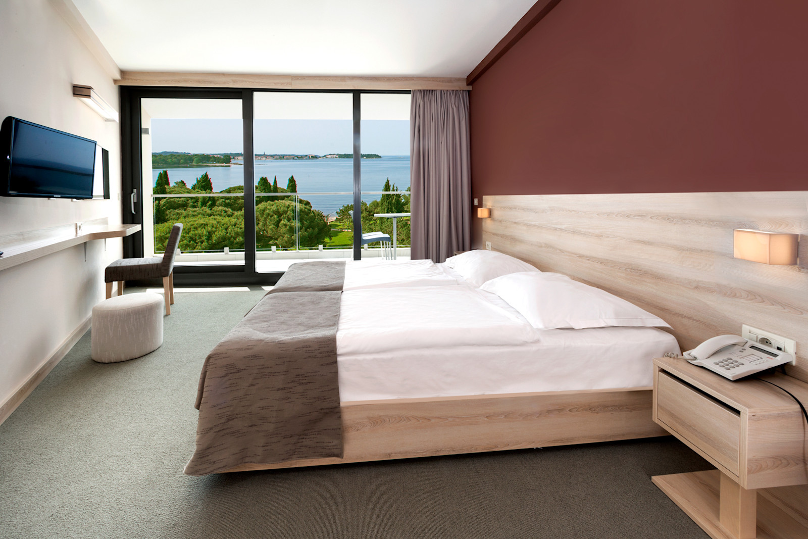 Helles Hotelzimmer mit Doppelbett und Aussicht auf das Wasser, modernen Möbeln und gemütlichem Ambiente.