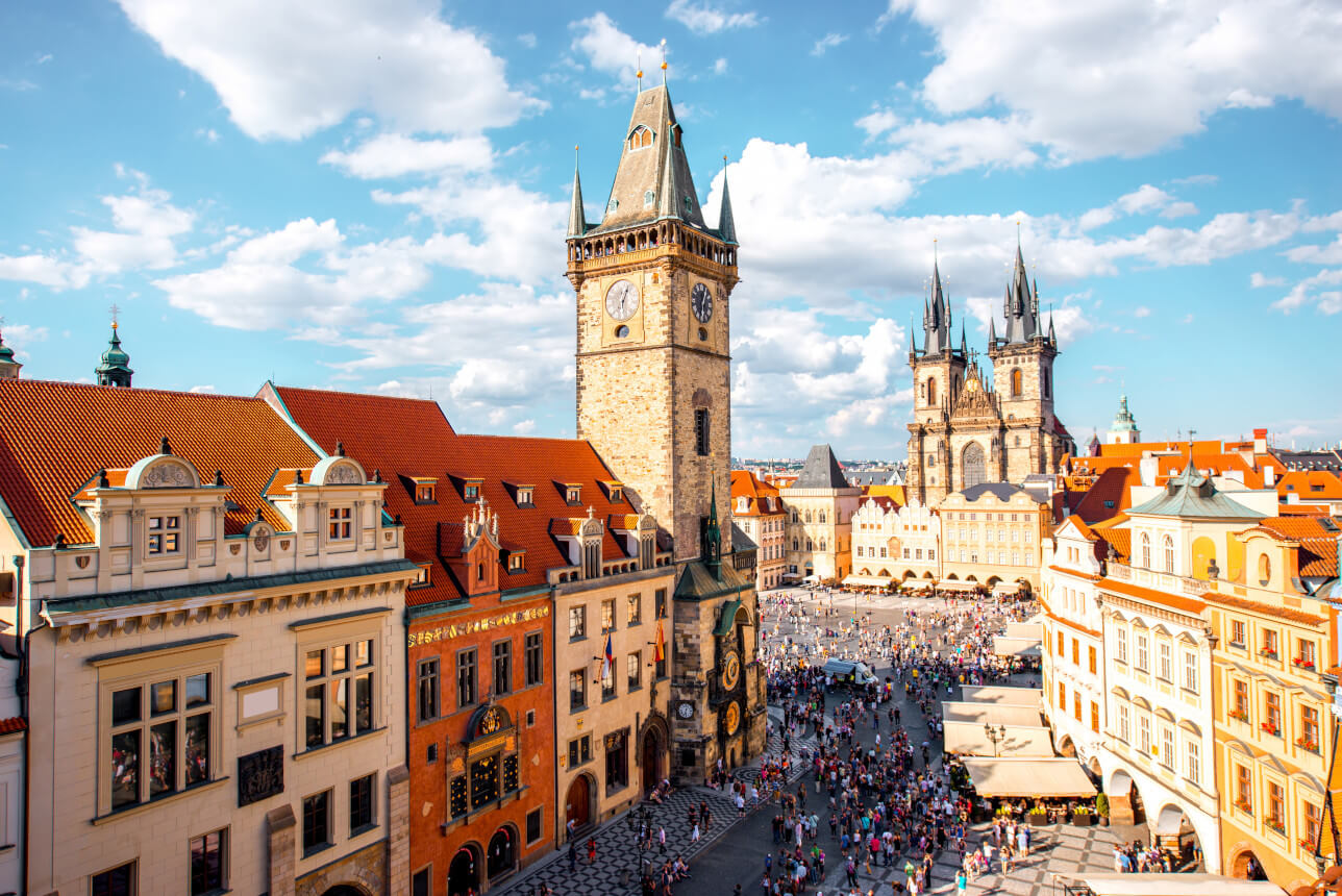 Der Wenzelsplatz in Prag mit dem imposanten Uhrenturm und bunten historischen Gebäuden unter blauem Himmel.