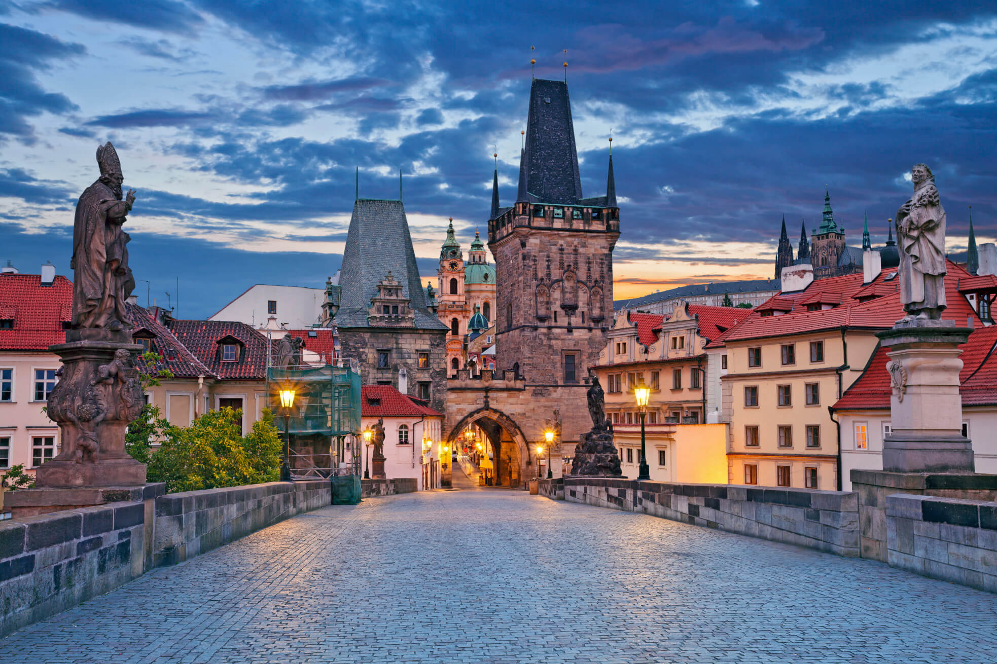 Die Karlsbrücke in Prag, umgeben von historischen Gebäuden und Statuen, im sanften Licht der Dämmerung.