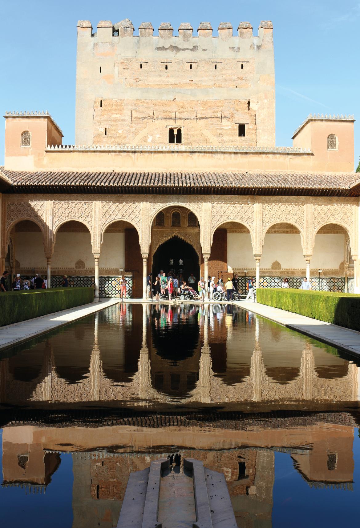 Ein schöner Innenhof mit Wasserspiegelung, umgeben von arabischer Architektur und zahlreichen Besuchern.