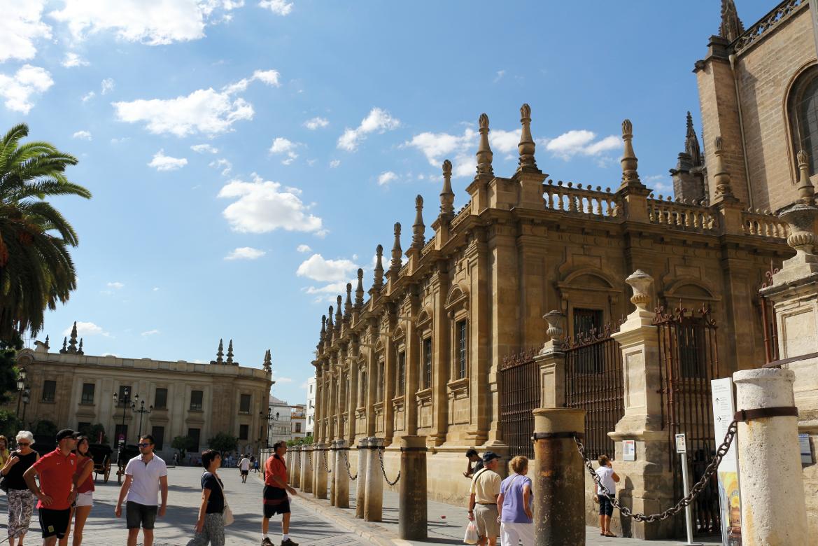 Ein sonniger Tag mit Menschen, die entlang einer historischen Gebäudezeile in einer Stadt spazieren.