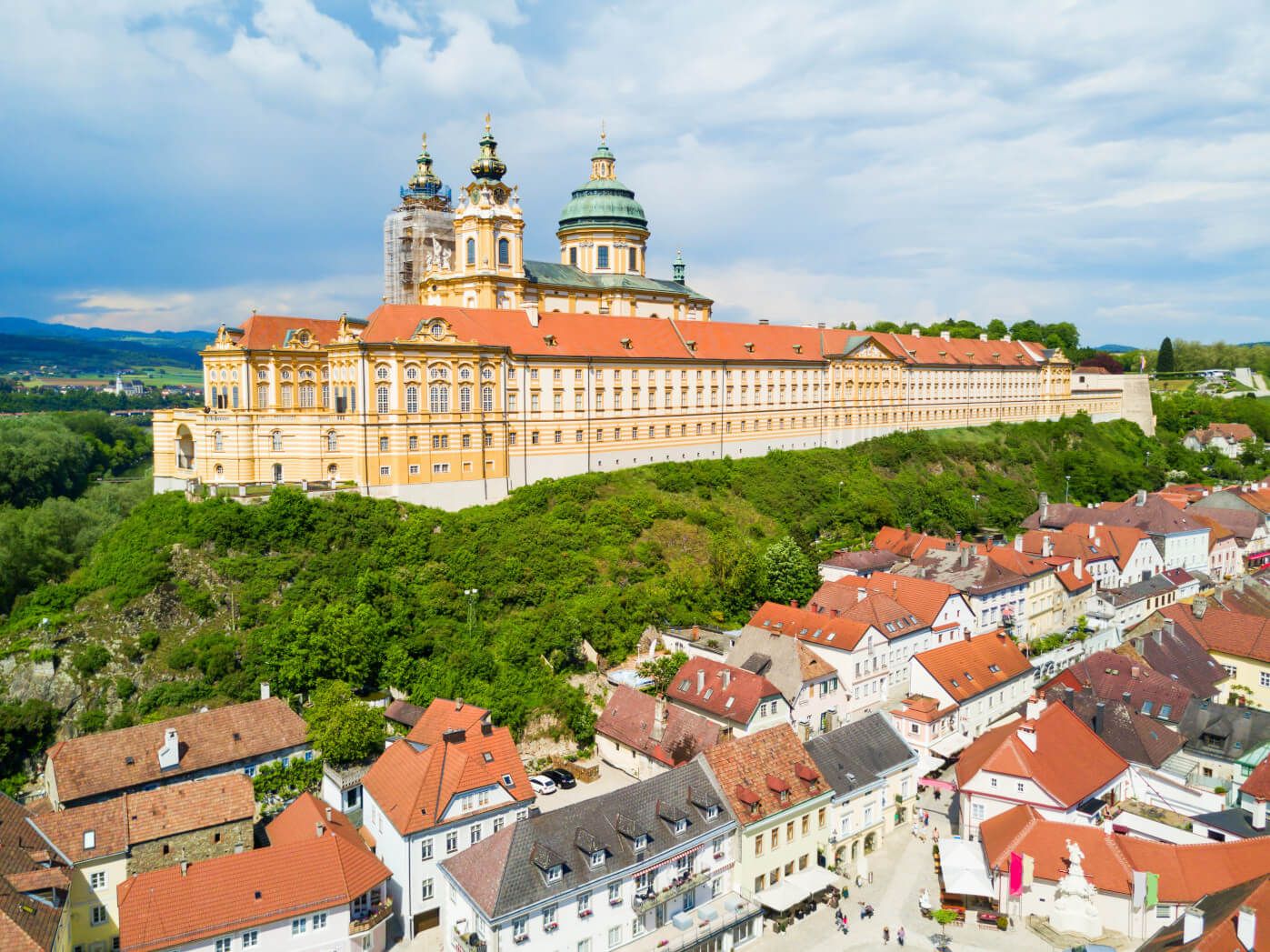Die prächtige Stiftskirche Melk thront über der Stadt, umgeben von grüner Landschaft und historischen Gebäuden.