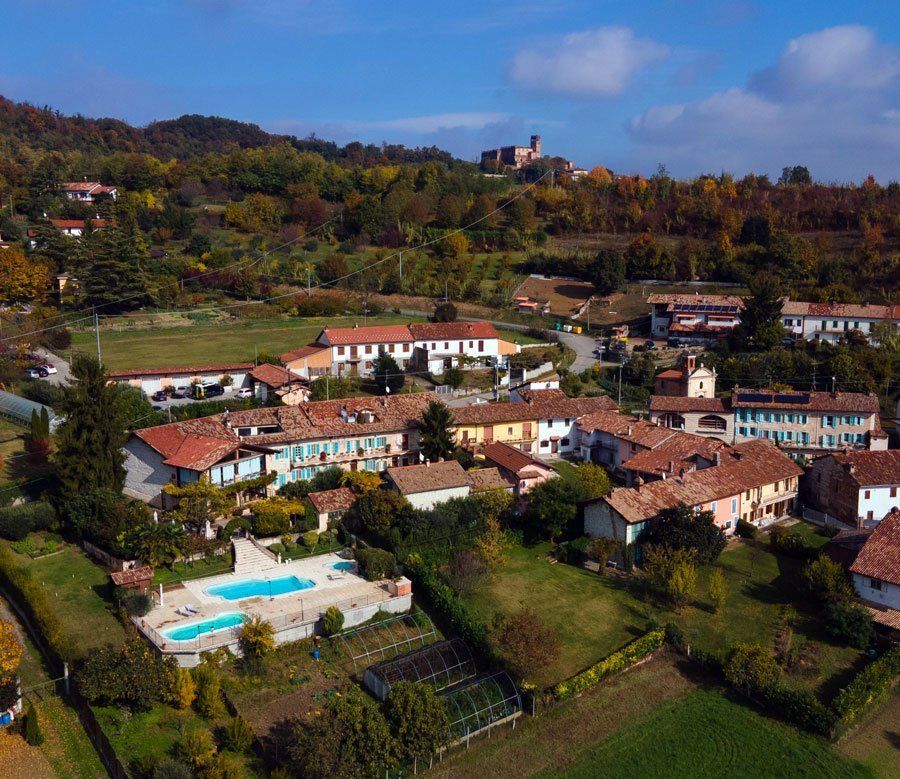 Ein malerisches Dorf mit bunten Häusern, einem Swimmingpool und einer hügeligen Landschaft im Hintergrund.