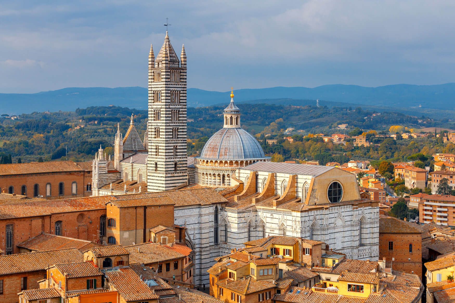 Die Bildbeschreibung zeigt die beeindruckende Kathedrale von Siena mit ihrem markanten Turm und der umliegenden Stadt.