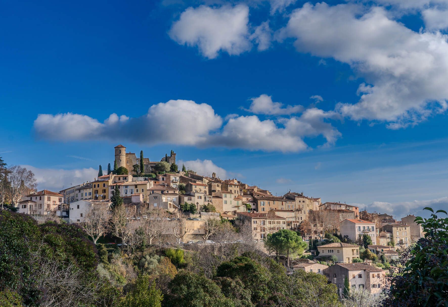 Eine malerische Stadt mit alten Gebäuden und einer Burg vor einem schönen blauen Himmel mit Wolken.