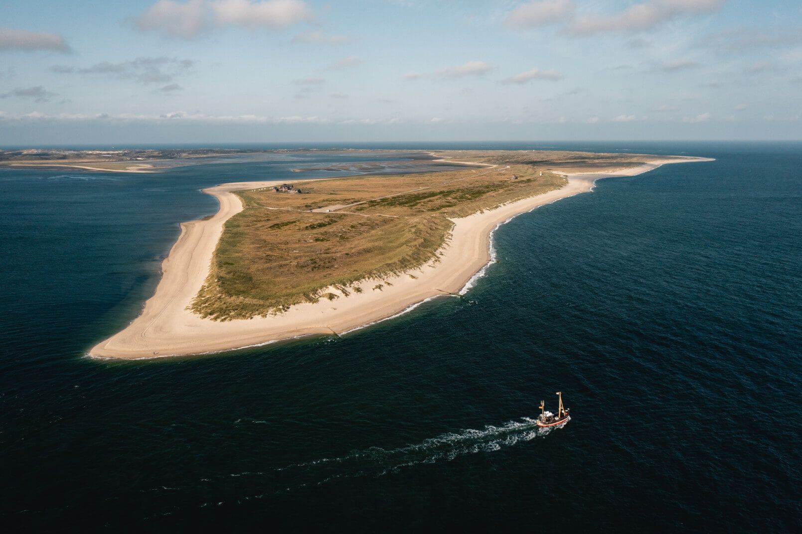 Eine malerische Insel mit Sandstränden und grünem Land, während ein Boot auf dem blauen Wasser fährt.