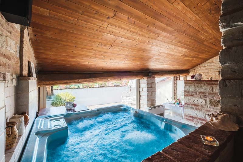 Whirlpool unter einem Holzdecke, viel Licht von Fenstern und gemütliche Atmosphäre, ideal zum Entspannen.