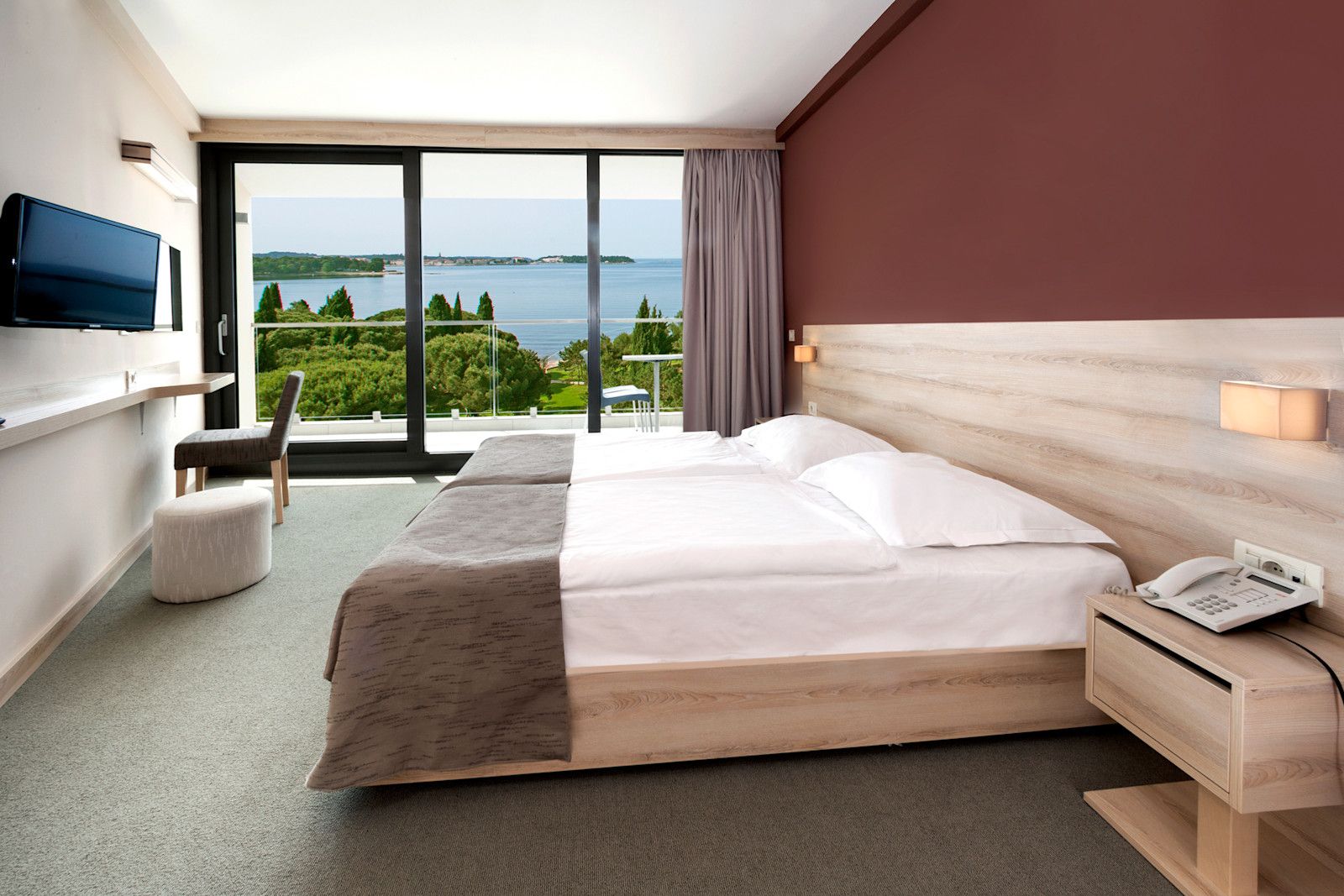 Helles Hotelzimmer mit Doppelbett und Aussicht auf das Wasser, modernen Möbeln und gemütlichem Ambiente.