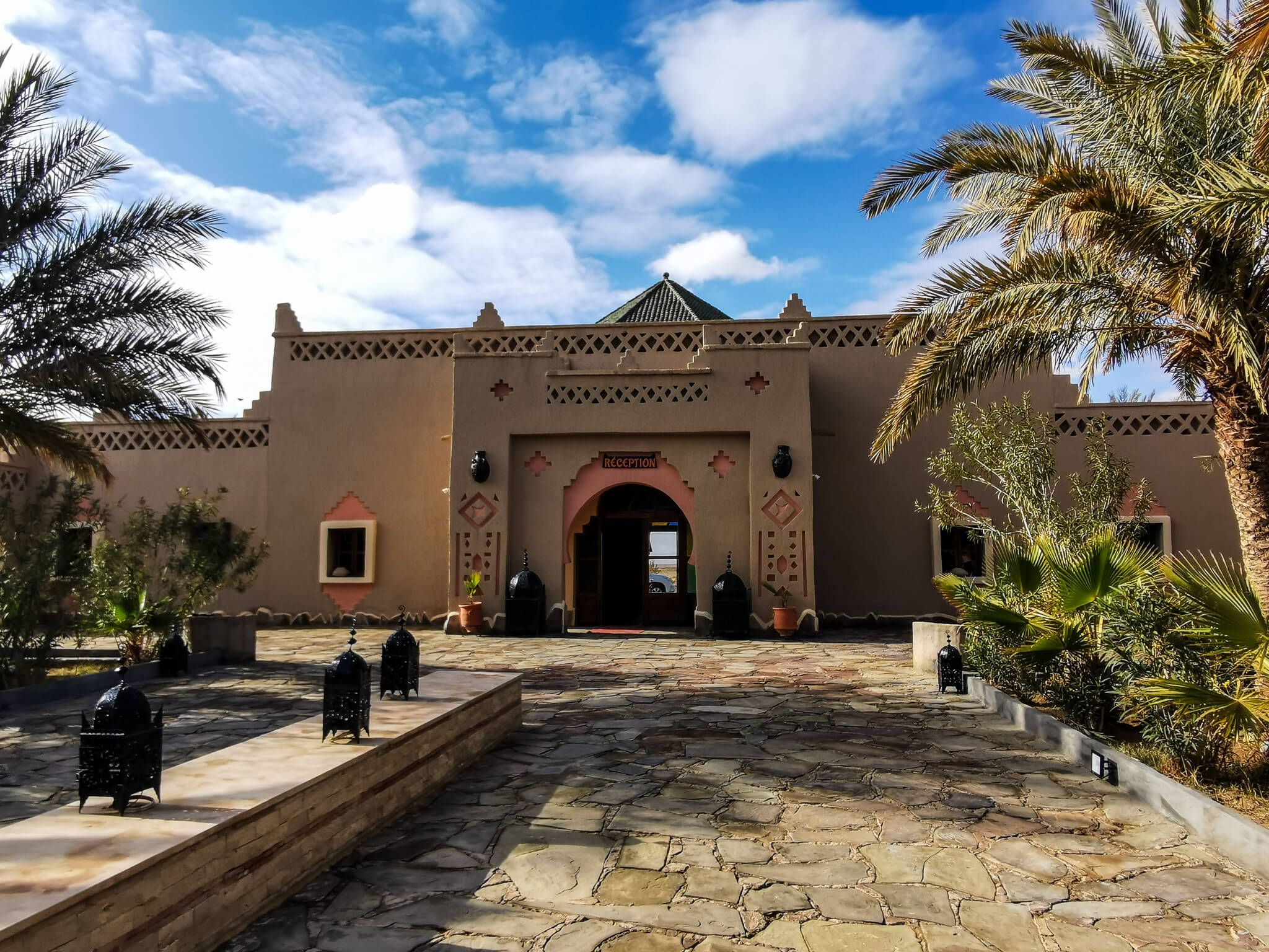 Ein traditionelles Gebäude mit Palmen, einem blauen Himmel und dekorativen Elementen lädt zum Entspannen ein.