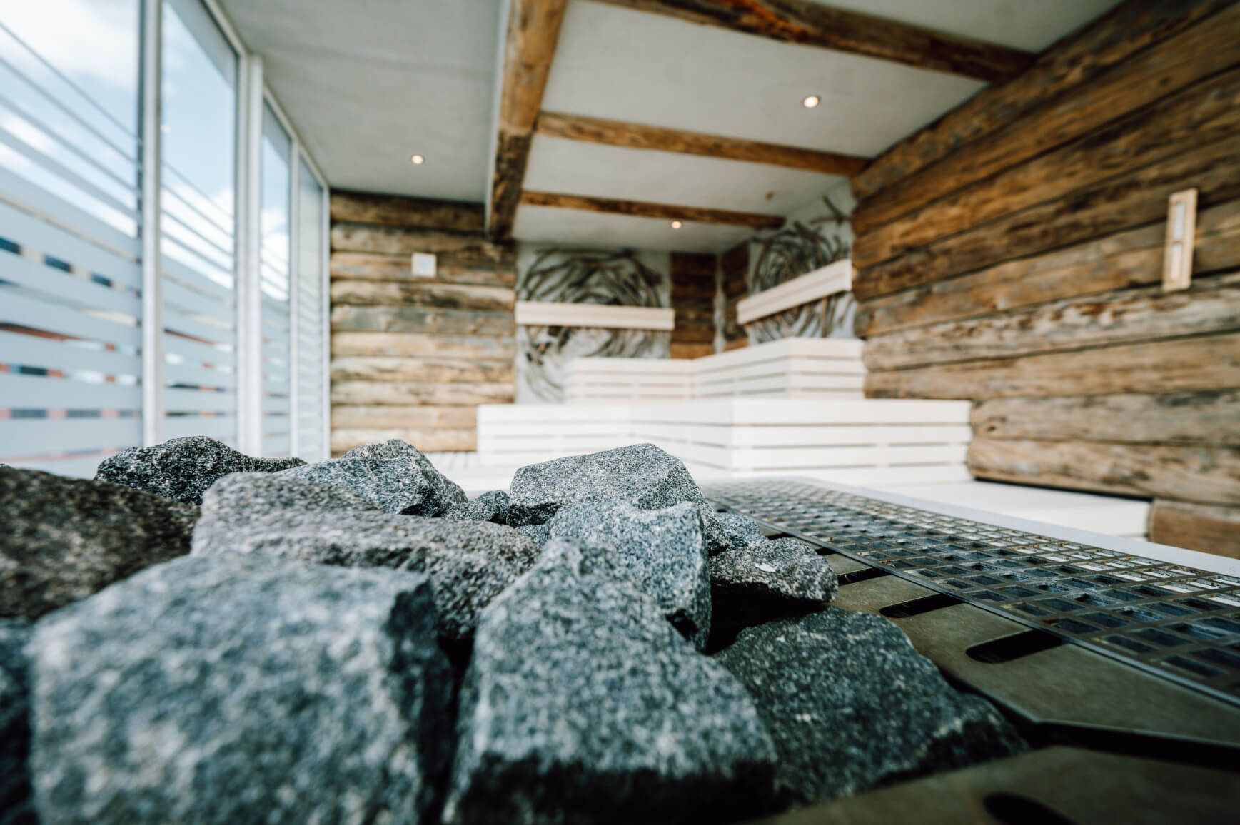 Ein moderner Saunabereich mit Holzverkleidung und einem Steinfeld für die Wärmequelle. Entspannende Atmosphäre.