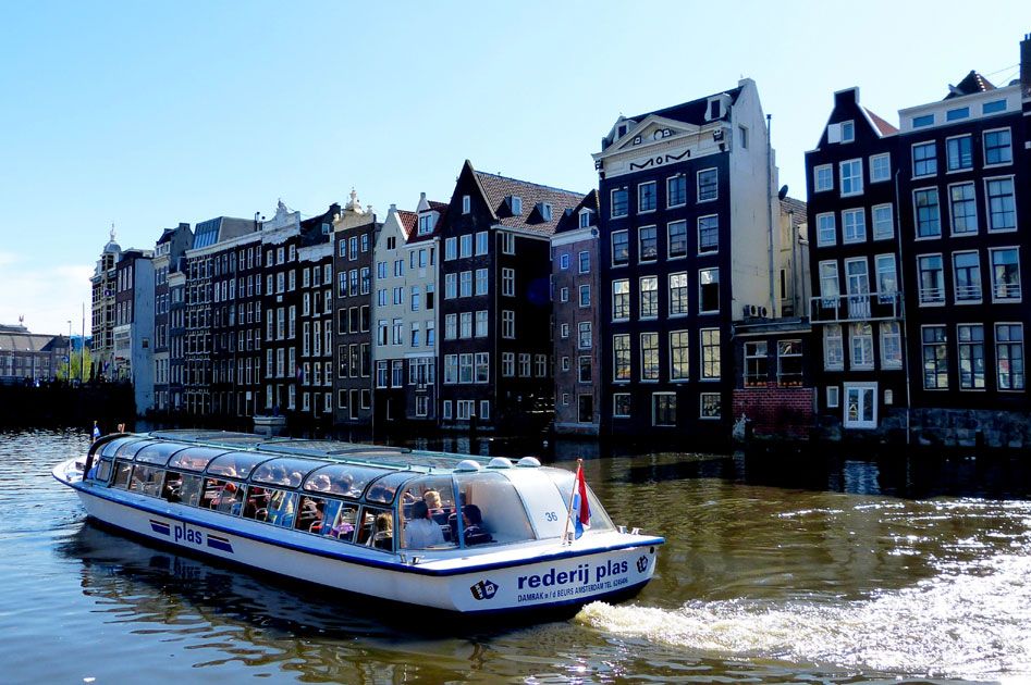 Ein Wassertaxi fährt an bunten, historischen Häusern entlang in einer malerischen Stadtlandschaft.