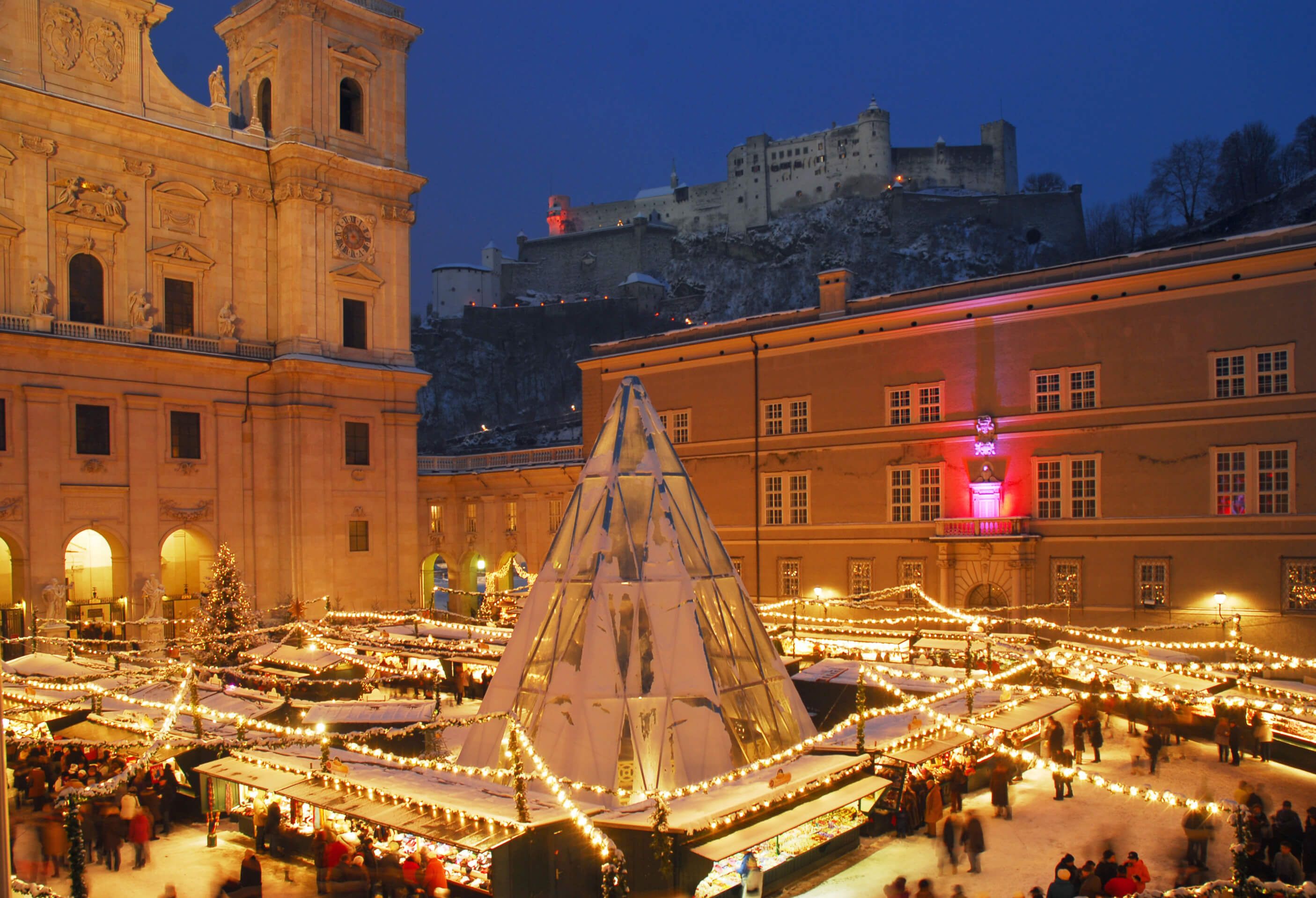 Ein stimmungsvoller Weihnachtsmarkt mit Lichtern, Ständen und einer beeindruckenden Kulisse in Salzburg.