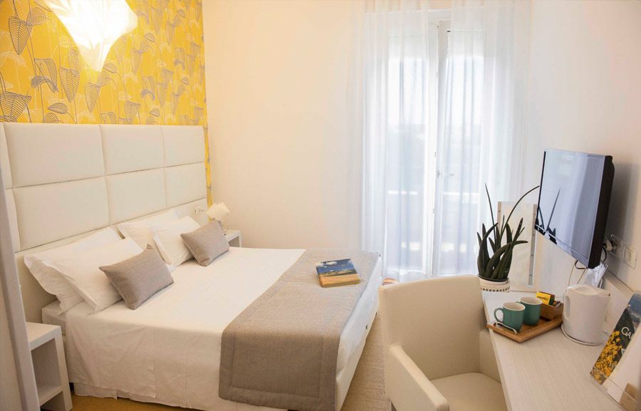 Ein modernes, helles Schlafzimmer mit einer gemütlichen Atmosphäre, TV, Schreibtisch und Balkonblick.