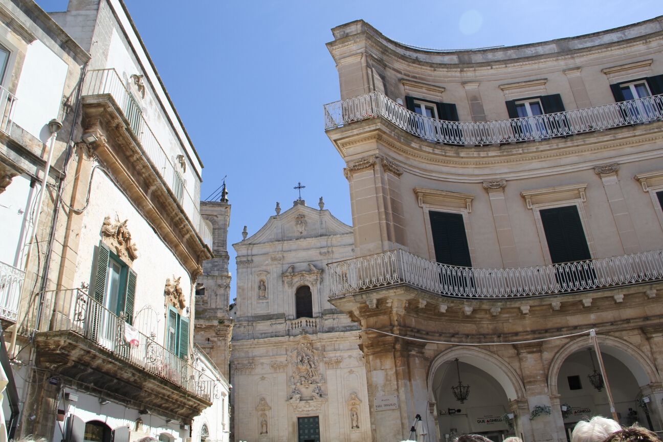 Eine malerische Stadtansicht mit historischen Gebäuden und einem klaren blauen Himmel. Verzierungen an den Fassaden.