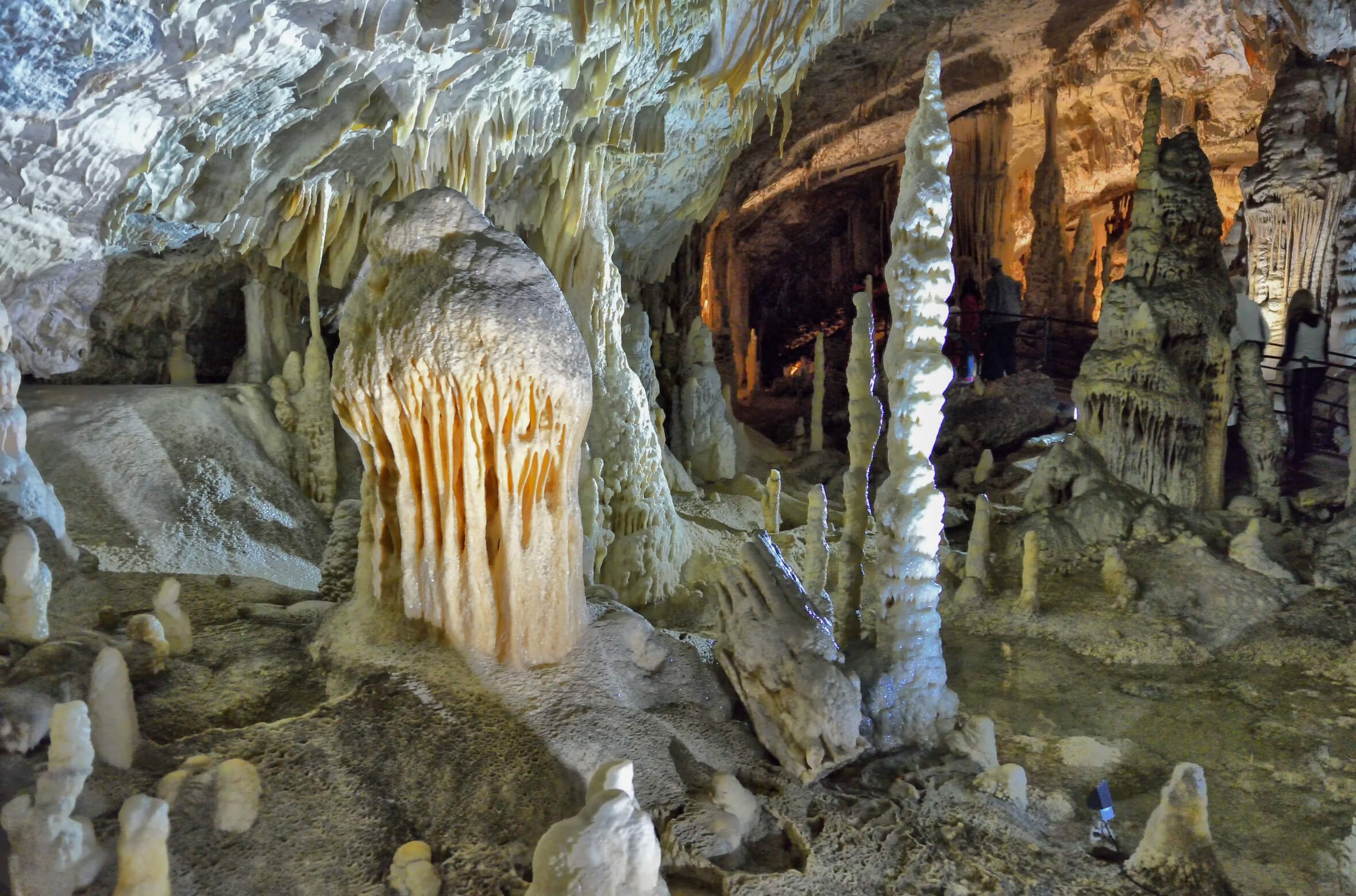 Eine beeindruckende Höhle mit Stalagmiten und Stalaktiten, beleuchtet und von Natur geformt. Mystische Atmosphäre.