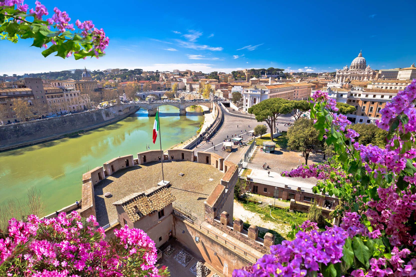 Eine malerische Aussicht auf Rom mit dem Tiber, historischen Gebäuden und blühenden Bougainvilleas im Vordergrund.