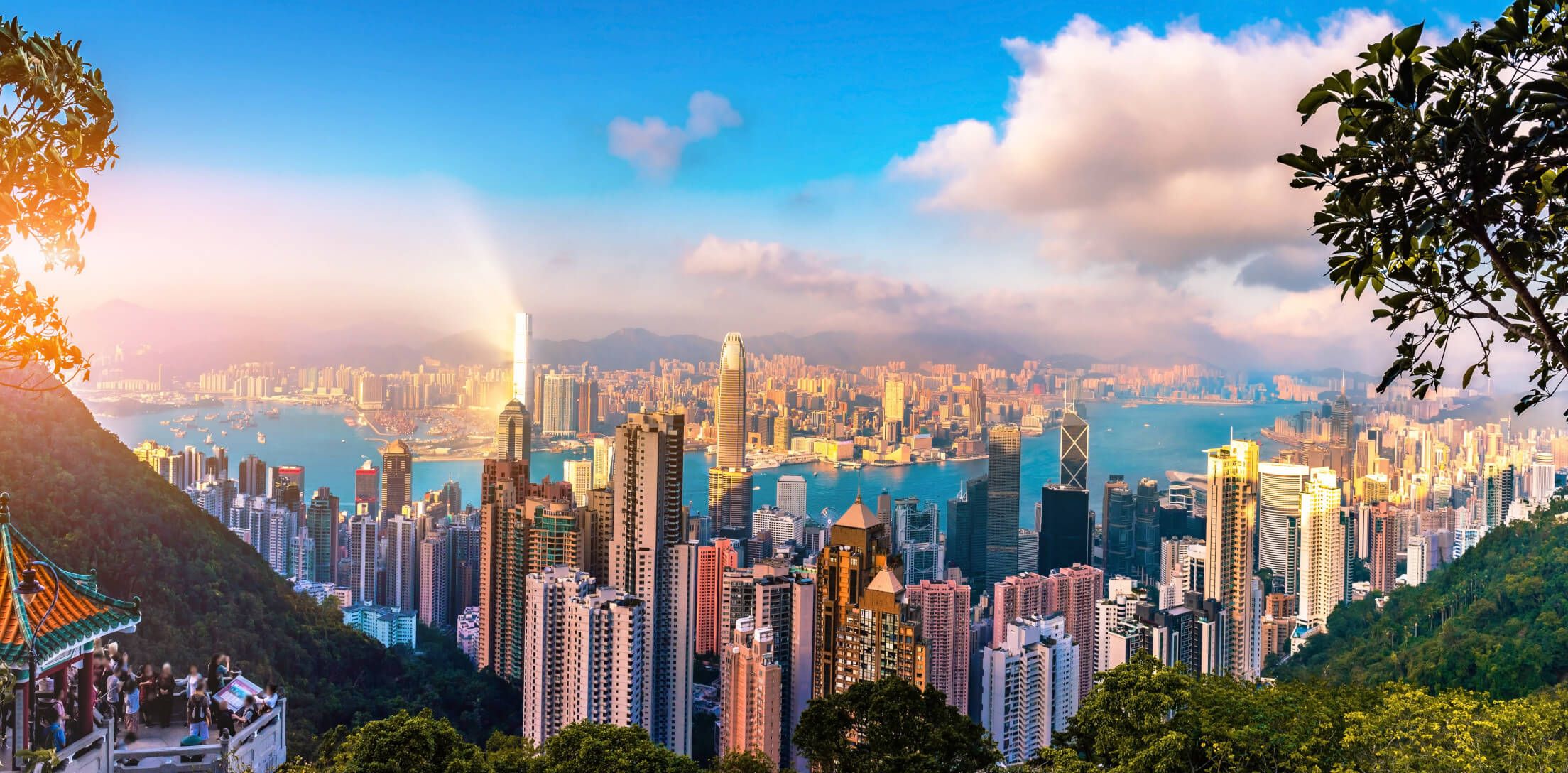 Blick auf die Skyline von Hongkong mit Wolkenkratzern und blauem Himmel. Eine malerische Hafenlandschaft.