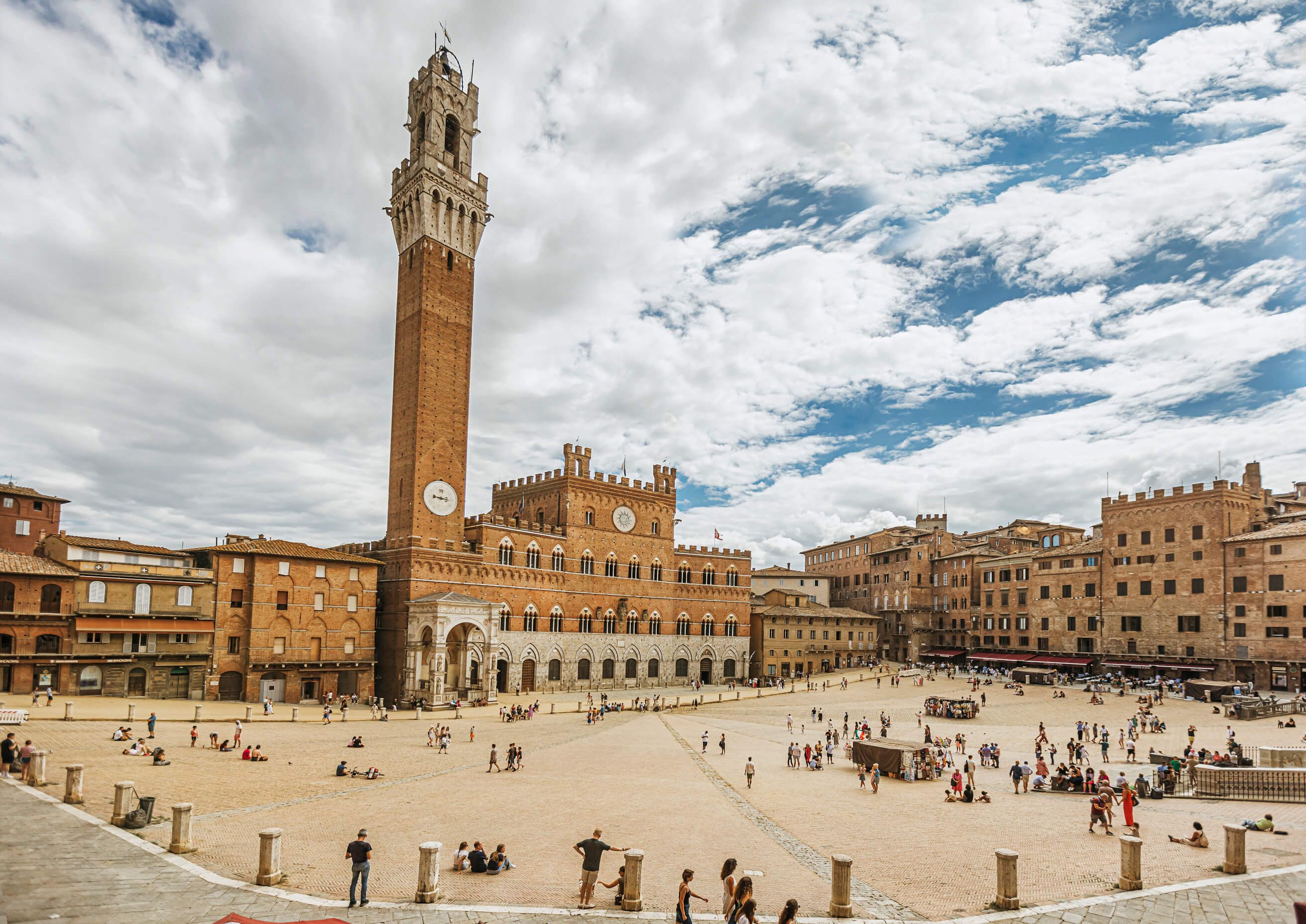 Der beeindruckende Platz in Siena mit dem hohen Turm und historischen Gebäuden, umgeben von Menschen.