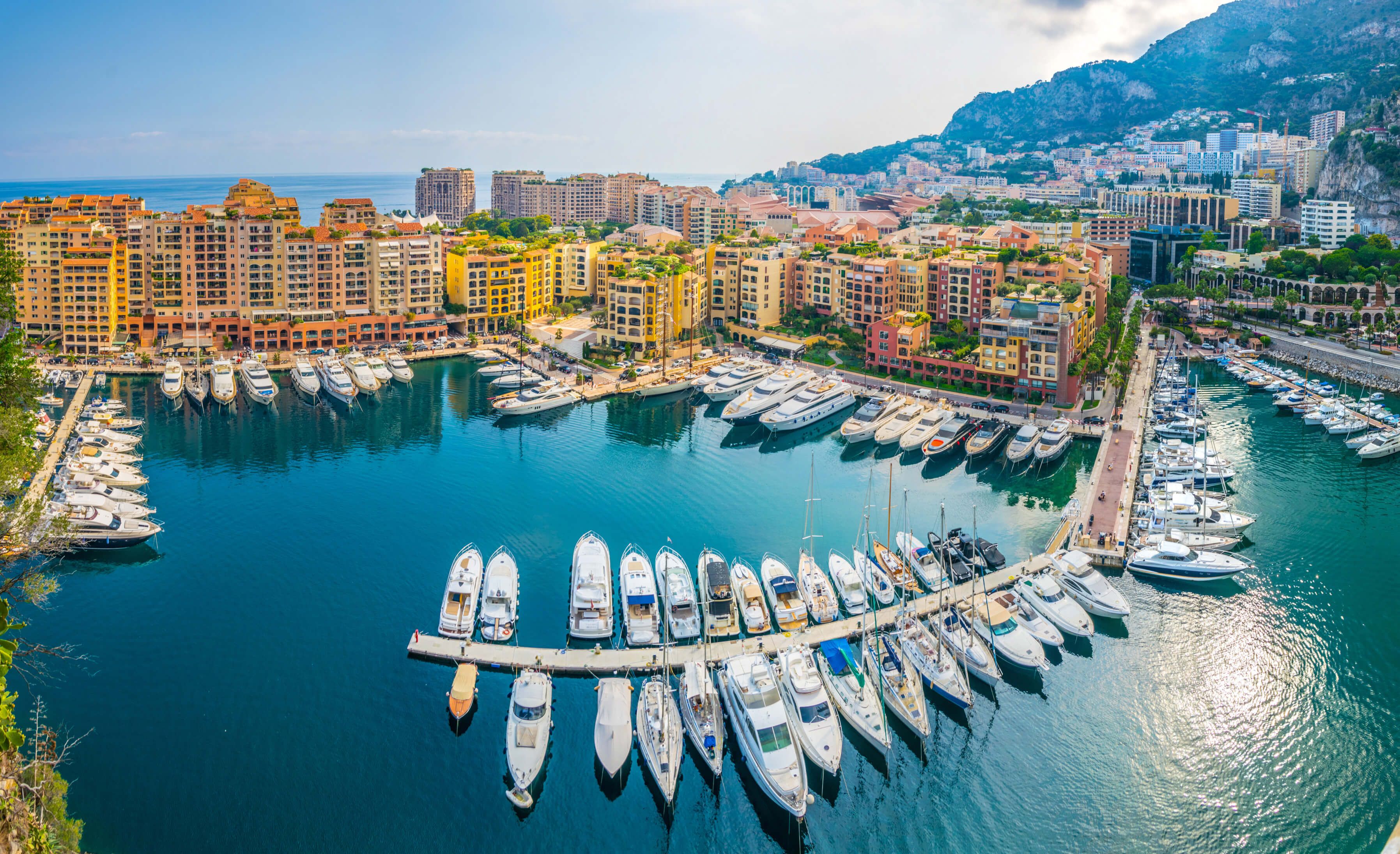 Eine Panoramaansicht des Yachthafens in Monaco, umgeben von bunten Gebäuden und klarem blauem Wasser.