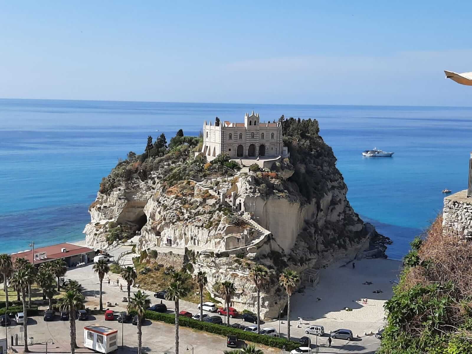 Eine malerische Küstenlandschaft mit einem Schloss auf einem Felsen und Blick auf das blaue Meer.