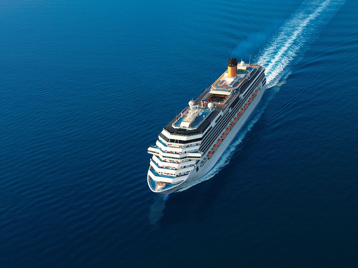 Ein großes Kreuzfahrtschiff fährt über das tiefblaue Wasser des Ozeans, hinterlässt eine Welle.