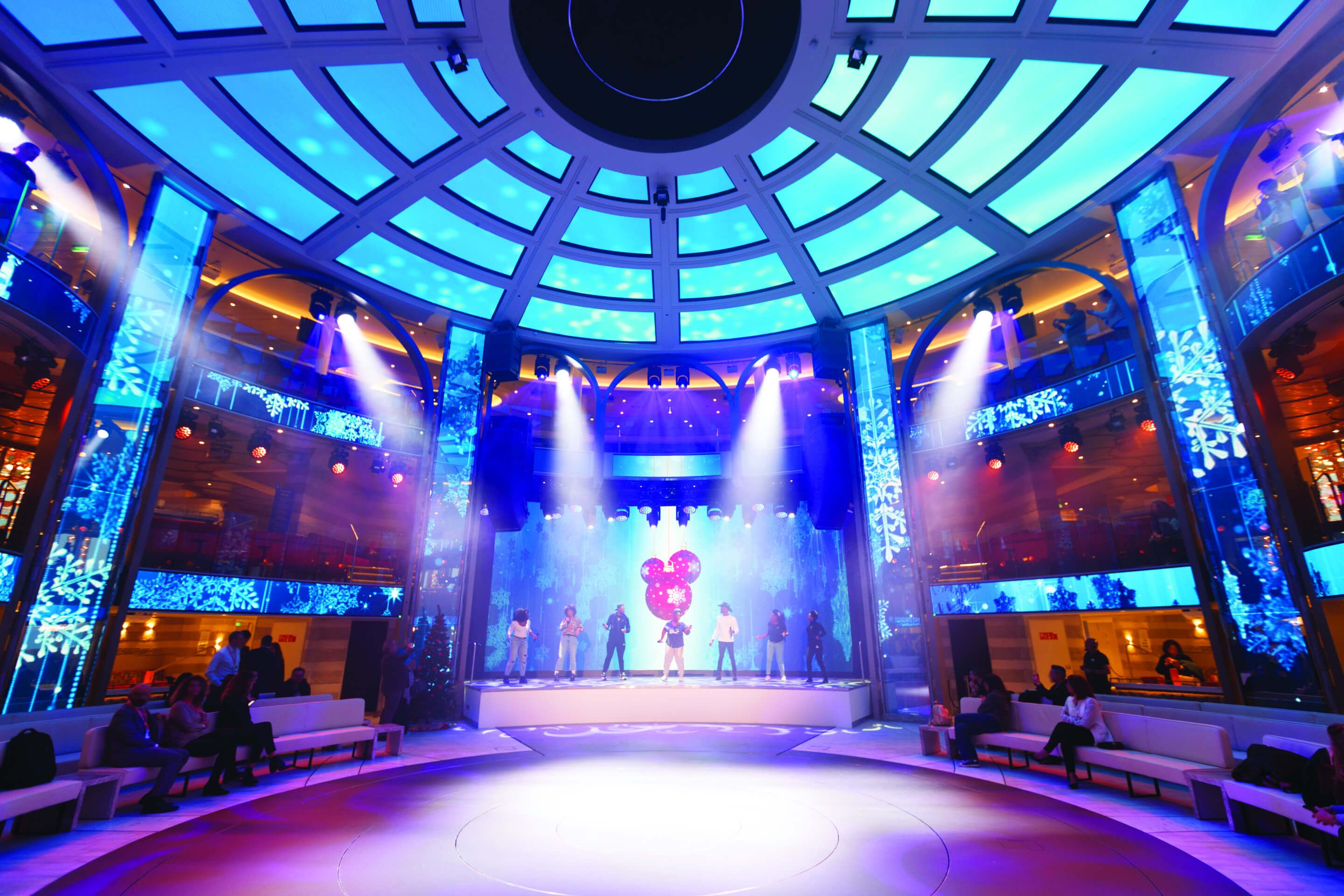 Eine Bühne mit bunten Lichtern und Tänzern, umgeben von einer modernen, stilvollen Kulisse.