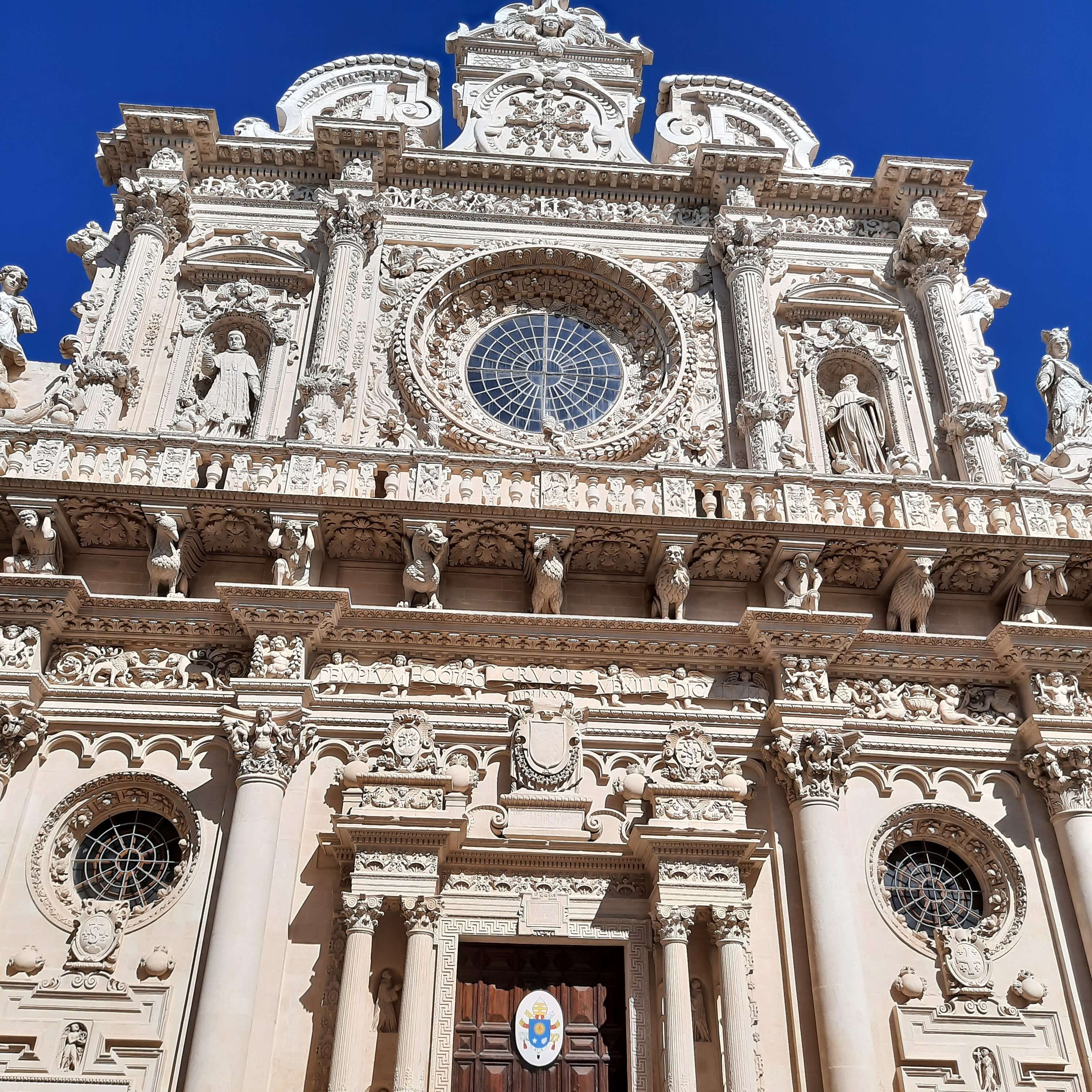 Prächtige, detailreiche Fassade einer historischen Kirche unter blauem Himmel, mit Skulpturen und Schmuckelementen.