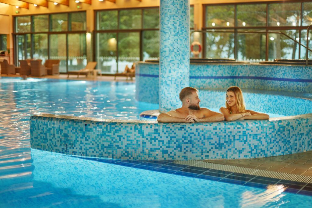 Ein Paar entspannt in einem blauen Schwimmbecken und genießt die Zeit zusammen in einer modernen Wellness-Umgebung.