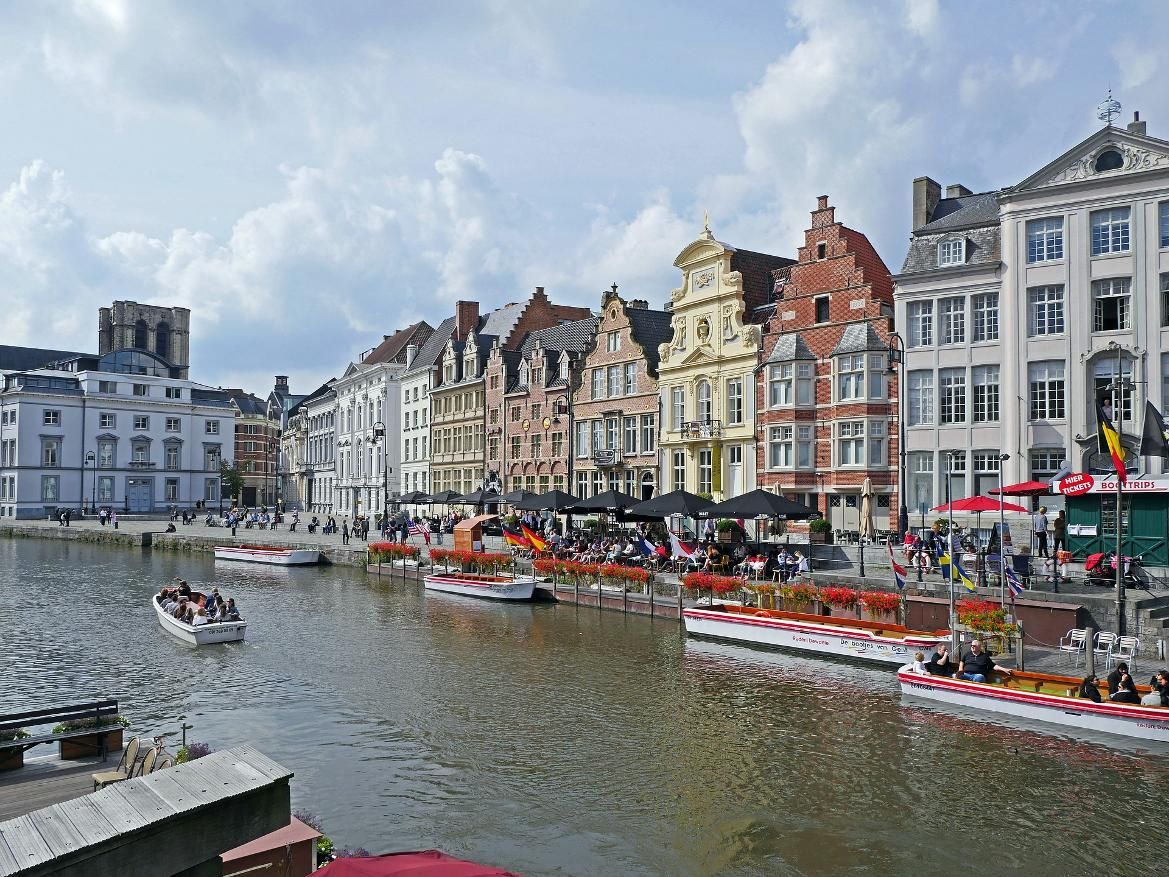 Bunte Häuser säumen den Kanal, während Boote fahren und Menschen die sonnige Atmosphäre genießen.