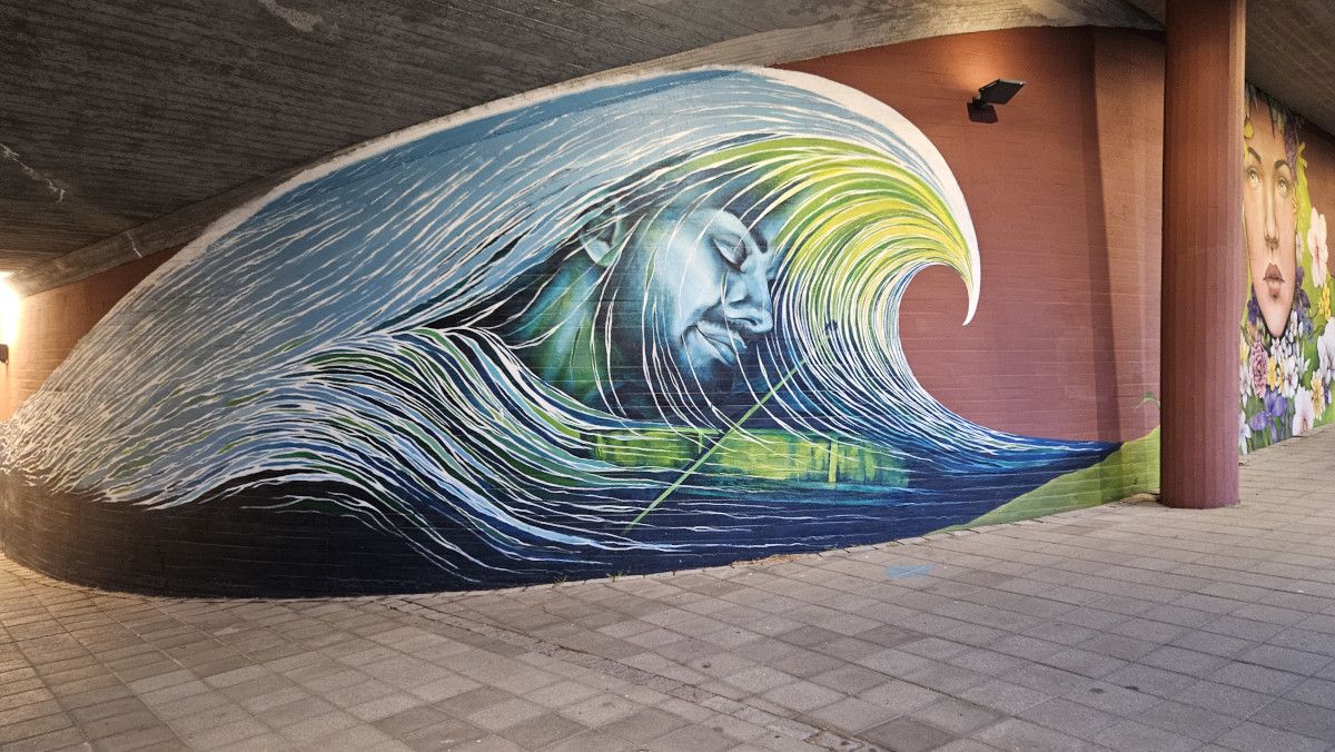 Ein faszinierendes Wandgemälde zeigt eine Welle und ein Gesicht, das in harmonischen Farben gestaltet ist.