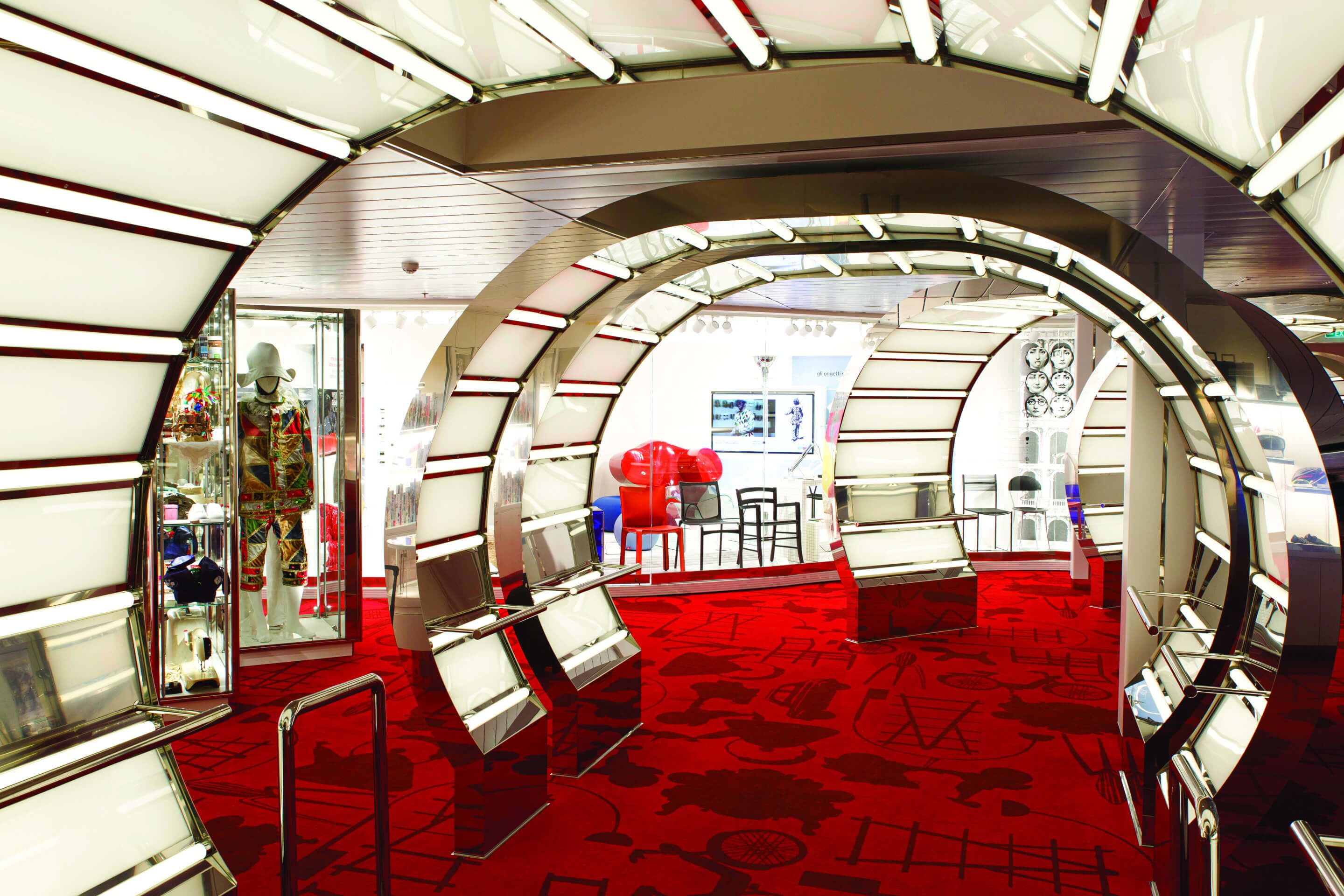 Ein futuristischer Ausstellungsraum mit roten Teppichen und illuminierenden Bögen, die verschiedene Kunstwerke zeigen.