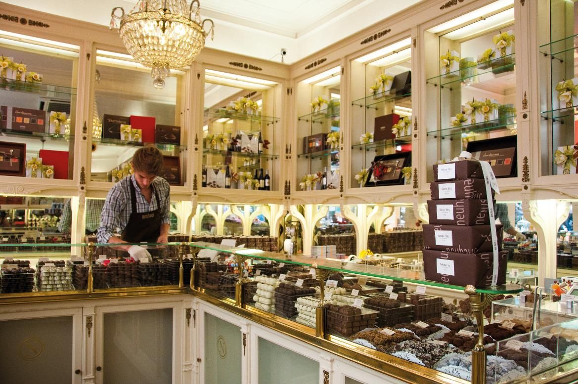 Ein Schokoladenladen mit einem Verkäufer, der Pralinen in einer eleganten Umgebung anordnet. Schöne Auslagen!