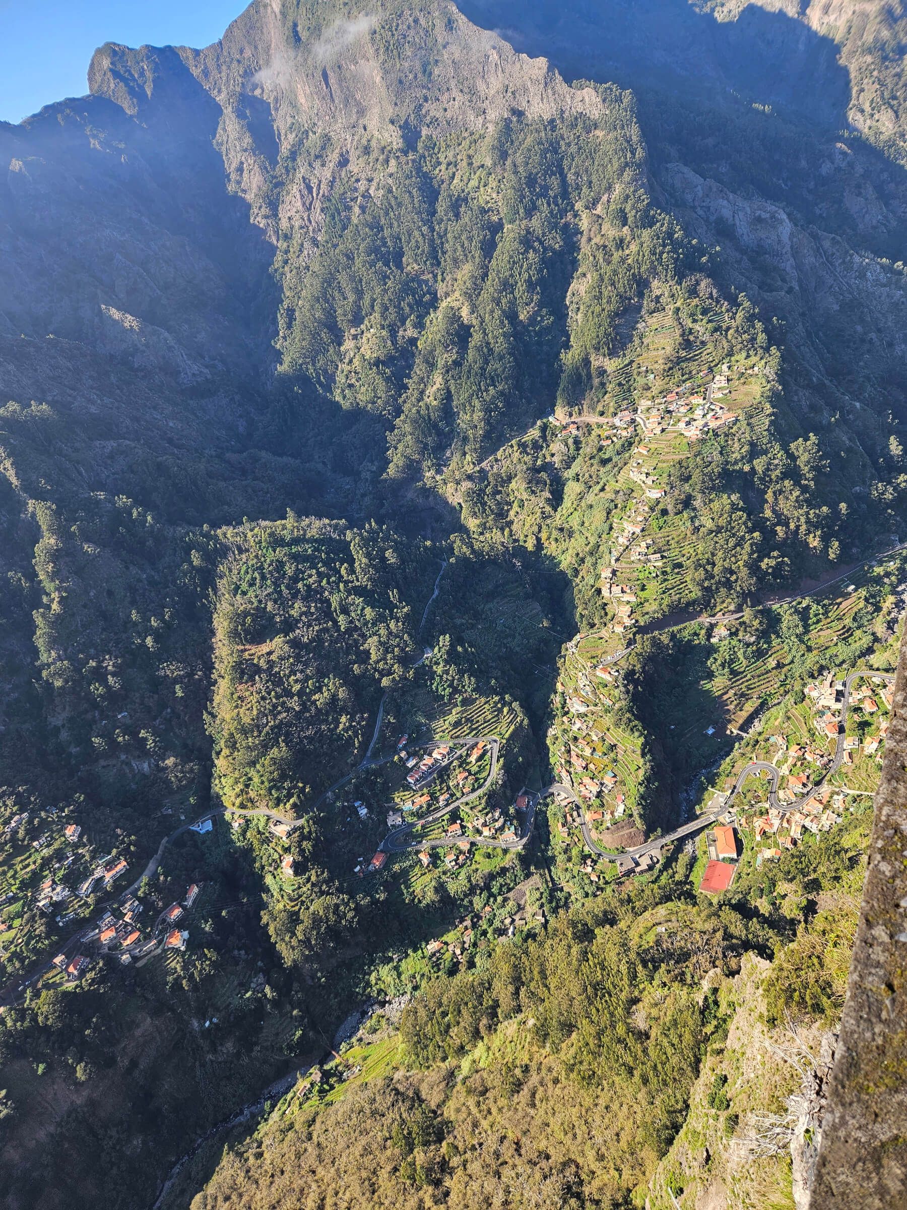 Eine atemberaubende Aussicht auf grüne Täler, Berge und verstreute Dörfer in einem malerischen Landschaftsbild.