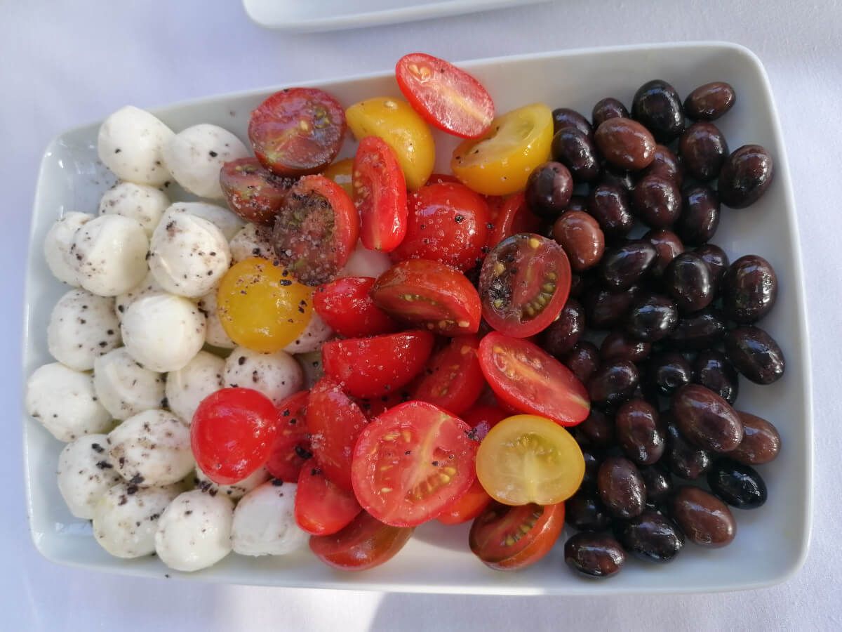 Frischer Teller mit Mozzarella, bunten Tomaten und schwarzen Oliven, appetitlich angeordnet.