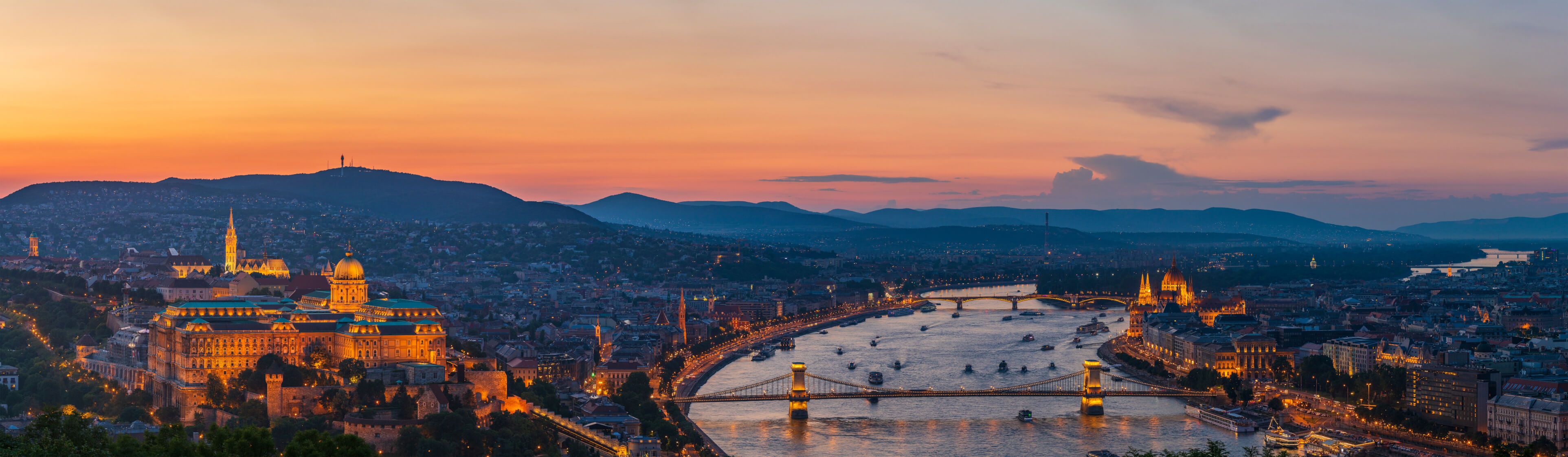 Die Panoramaansicht von Budapest zeigt den Fluss Donau bei Sonnenuntergang, beleuchtet von schönem Stadtlicht.