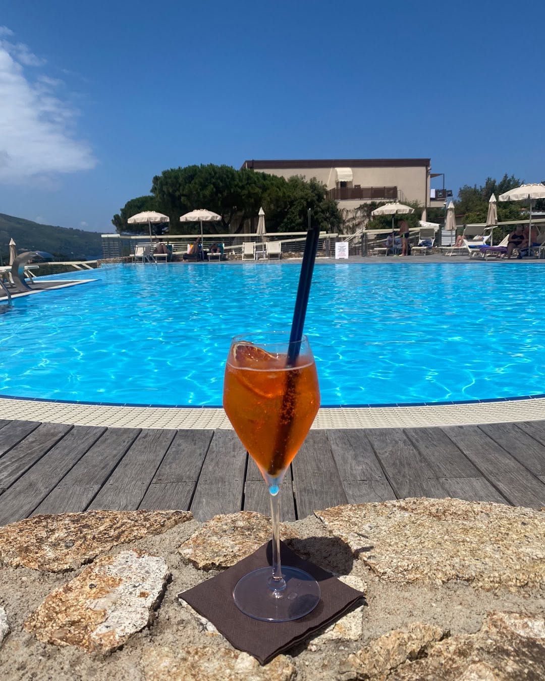 Ein erfrischender Drink am Pool des Hotels La Perla del Golfo steht am Rande eines strahlend blauen Pools unter einem klaren Himmel.