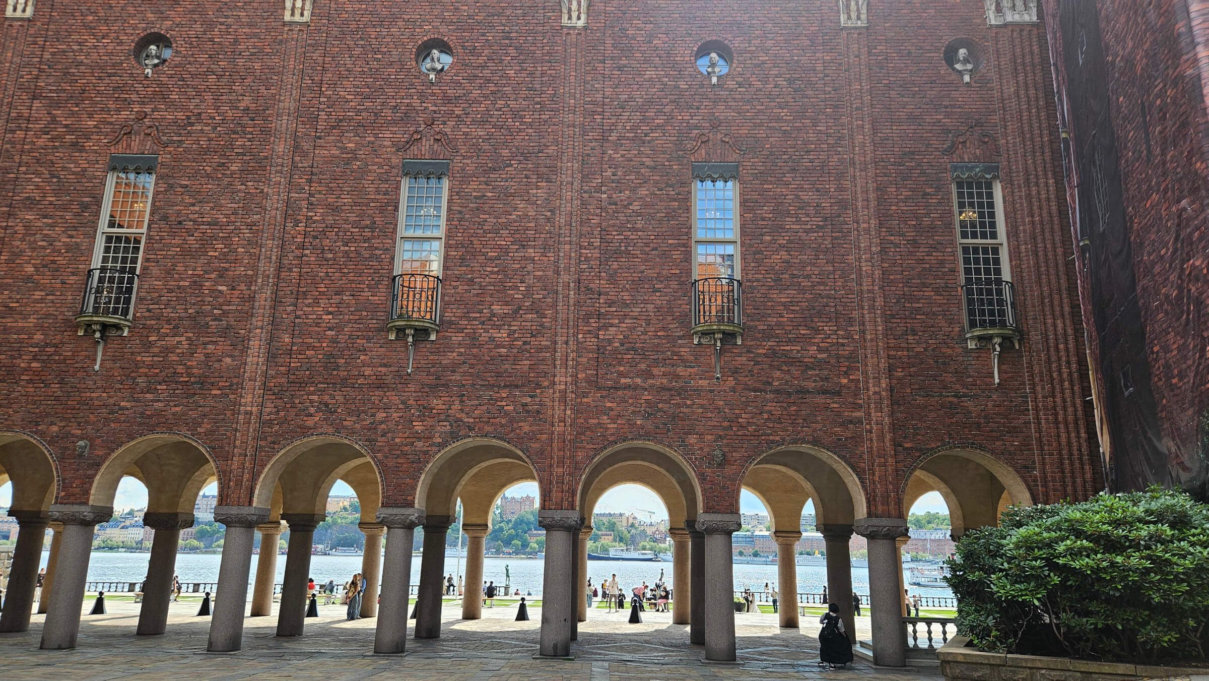 Ein Blick auf eine architektonische Struktur mit roten Ziegeln und Bögen, Blick auf das Wasser im Hintergrund.