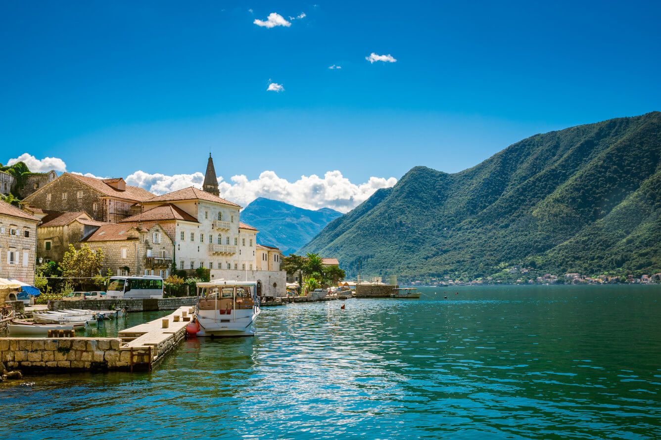 Idyllische Küstenstadt mit Bergen im Hintergrund und Booten im klaren Wasser. Perfekte Umgebung für Entspannung!