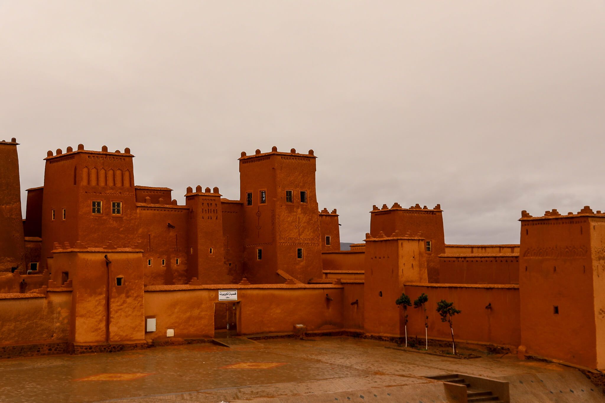 Eine beeindruckende Lehmburg mit orangefarbenen Wänden und Türmen unter einem grauen Himmel. Historisches Bauwerk.