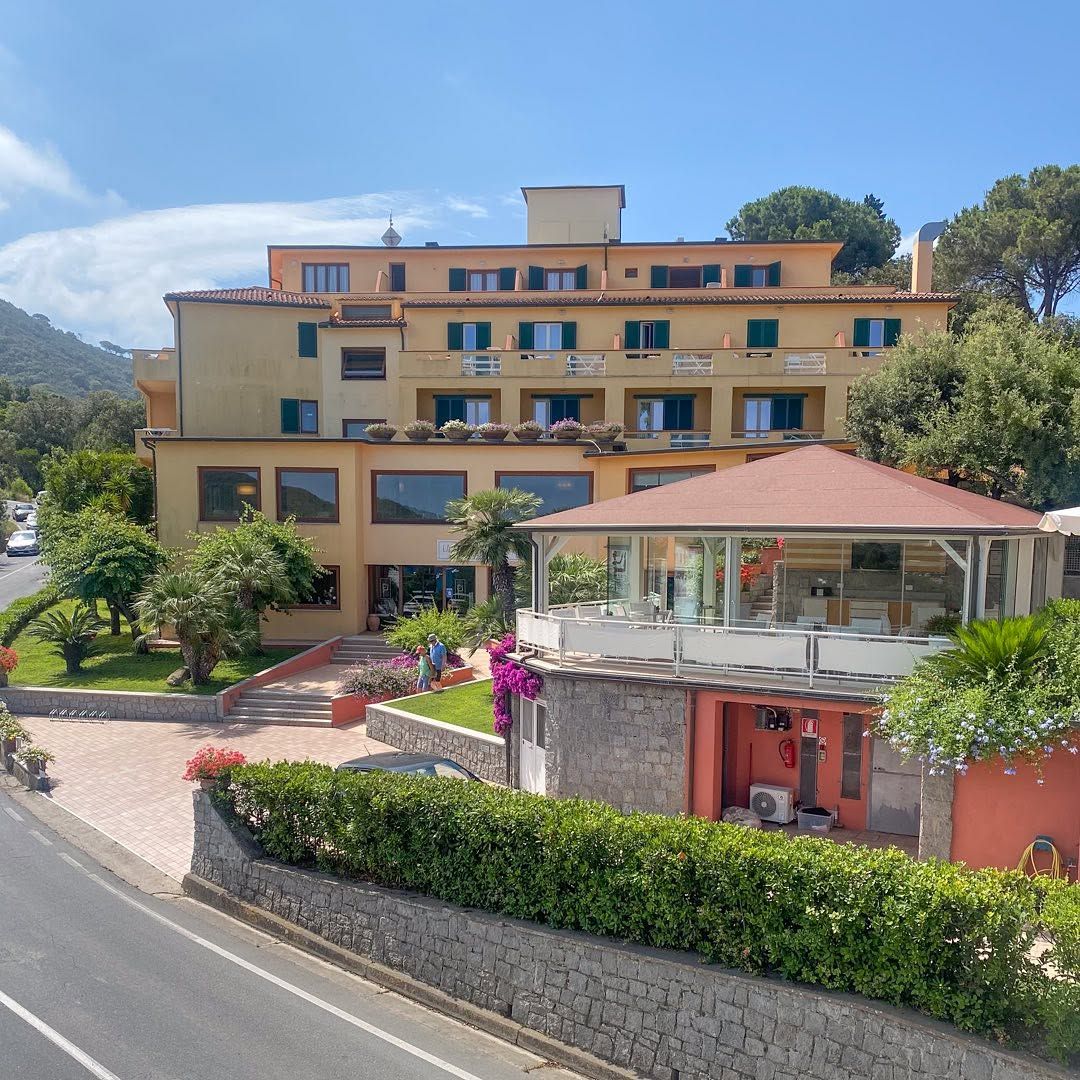 Ein modernes Gebäude mit bunten Pflanzen, gelegen an einer Straße, umgeben von Natur und Bergen.