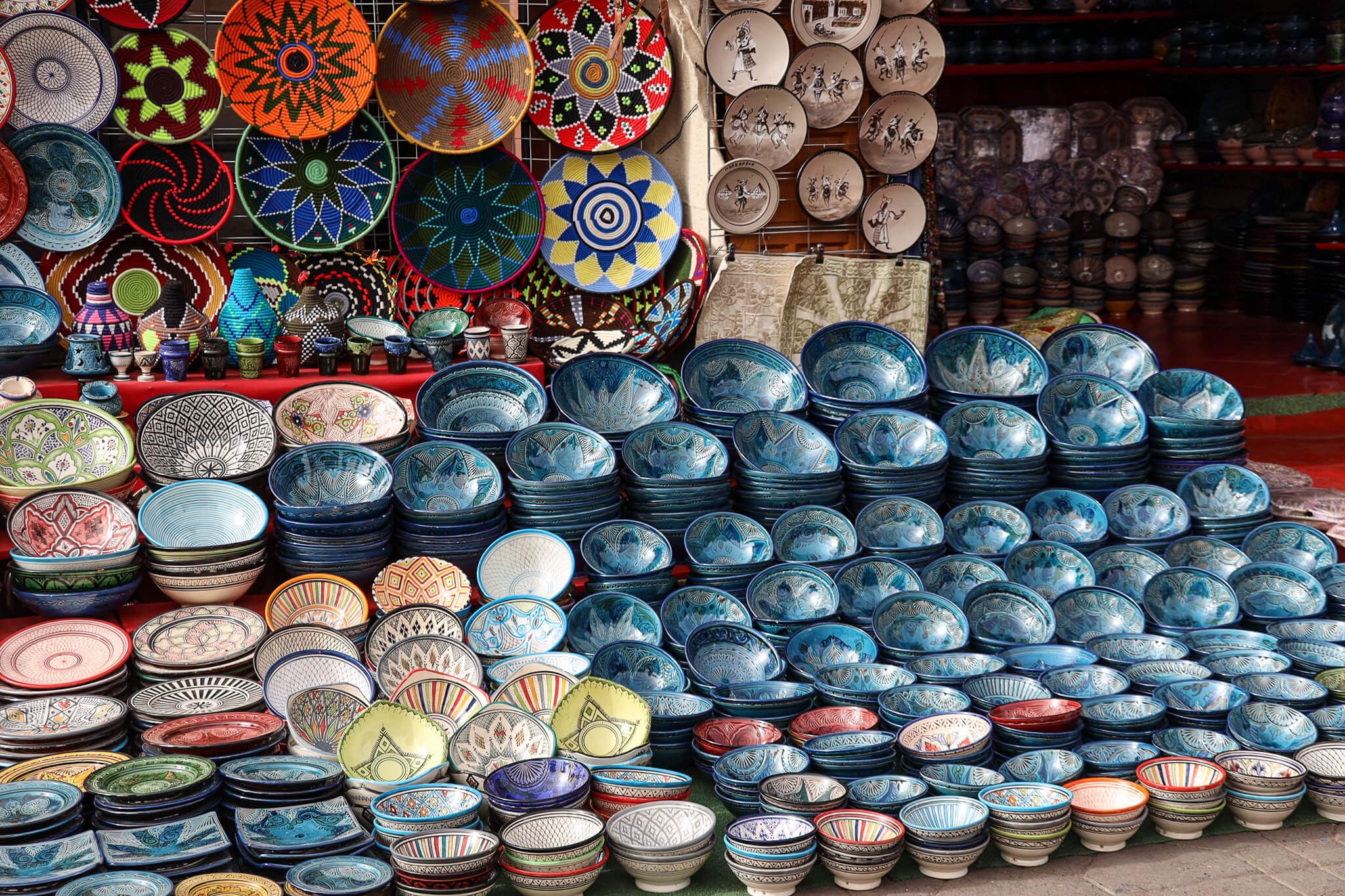 Bunte Keramikteller und Schalen in verschiedenen Formen und Mustern, ausgestellt auf einem Markt.